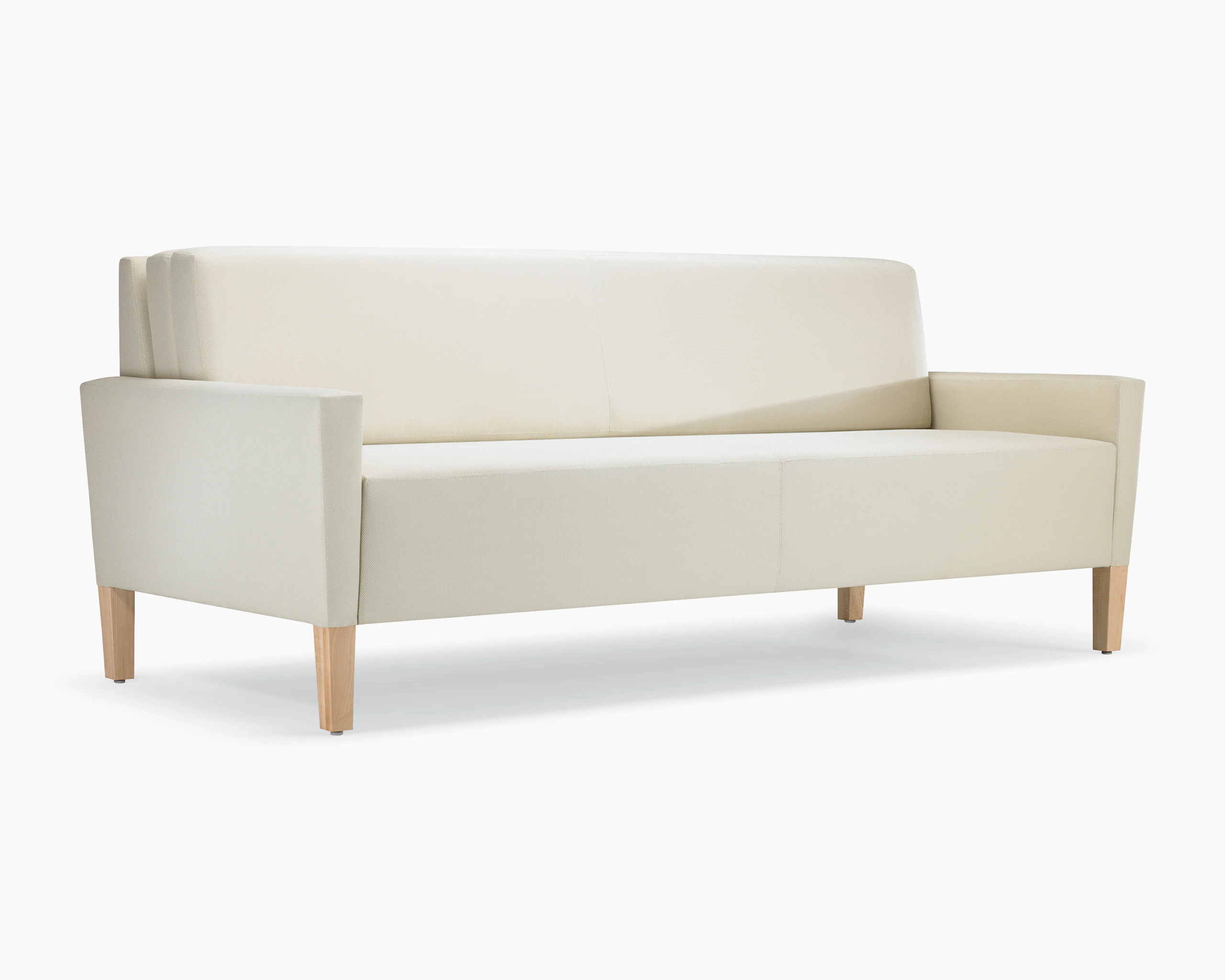 A three-quarter view of a Brava Flop Sofa in white textile with maple legs.