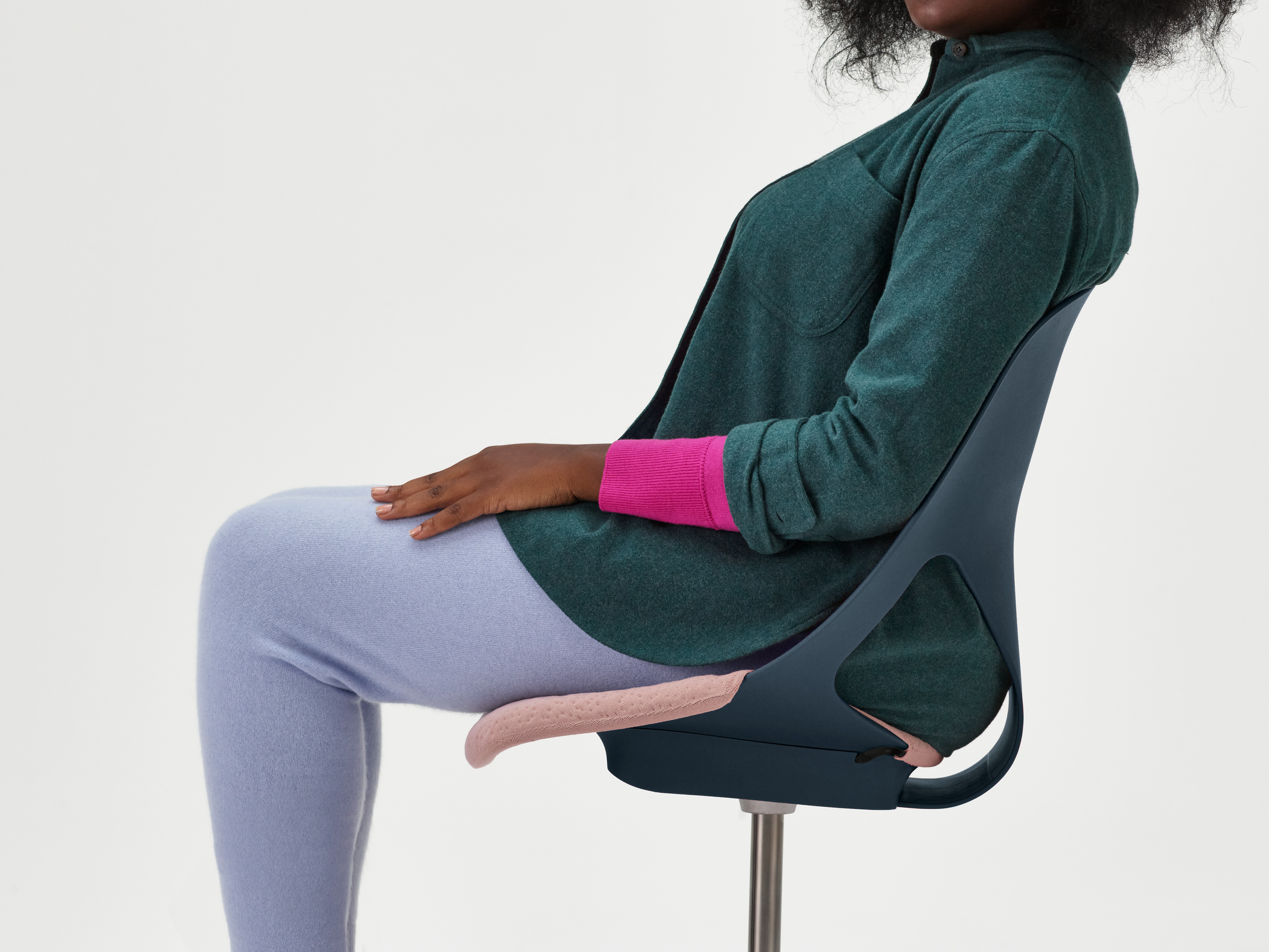A woman sitting in a red Zeph chair without arms and pink seat cover.