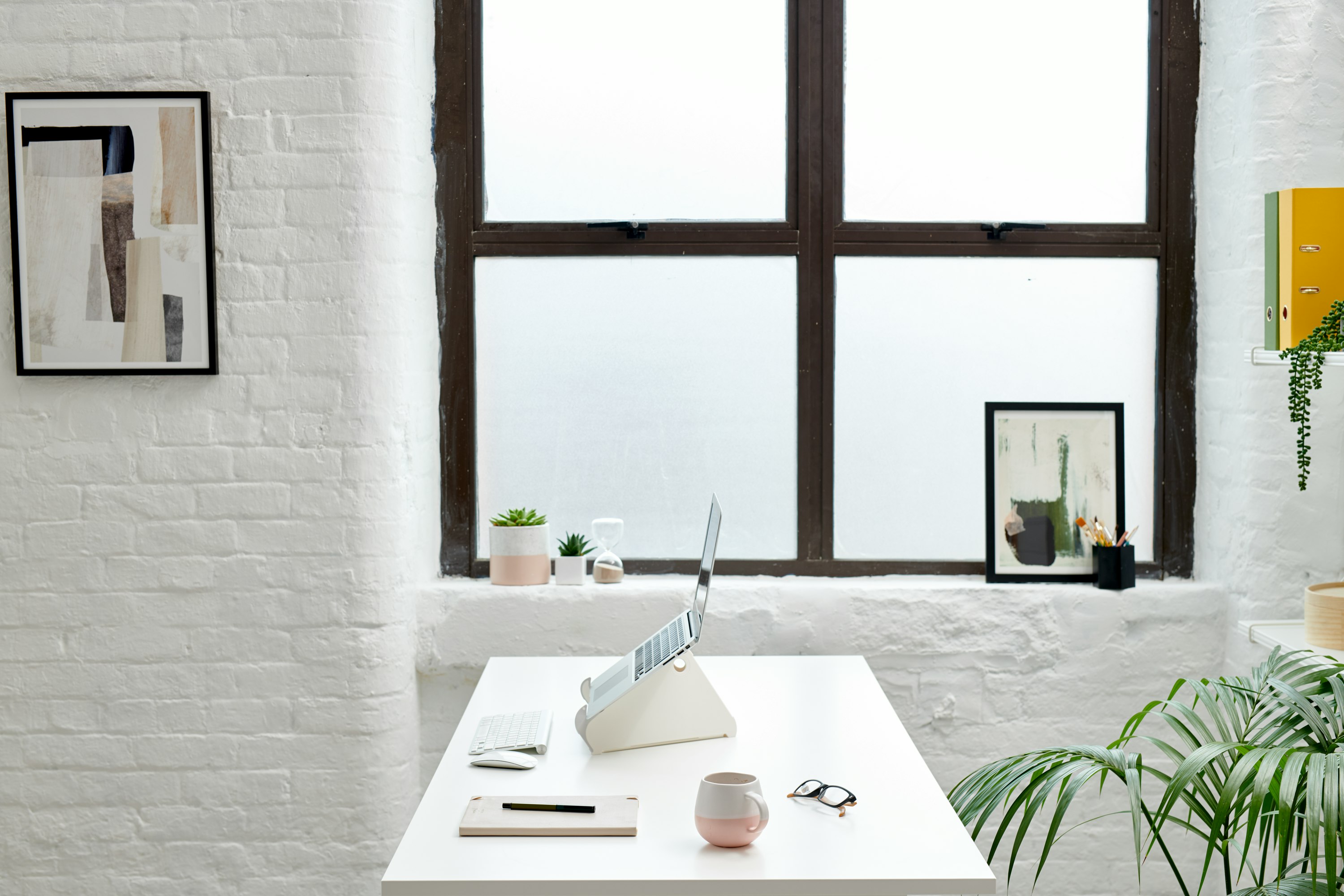 A side view of an Oripura Laptop Stand positioned on a desk in a small office space.