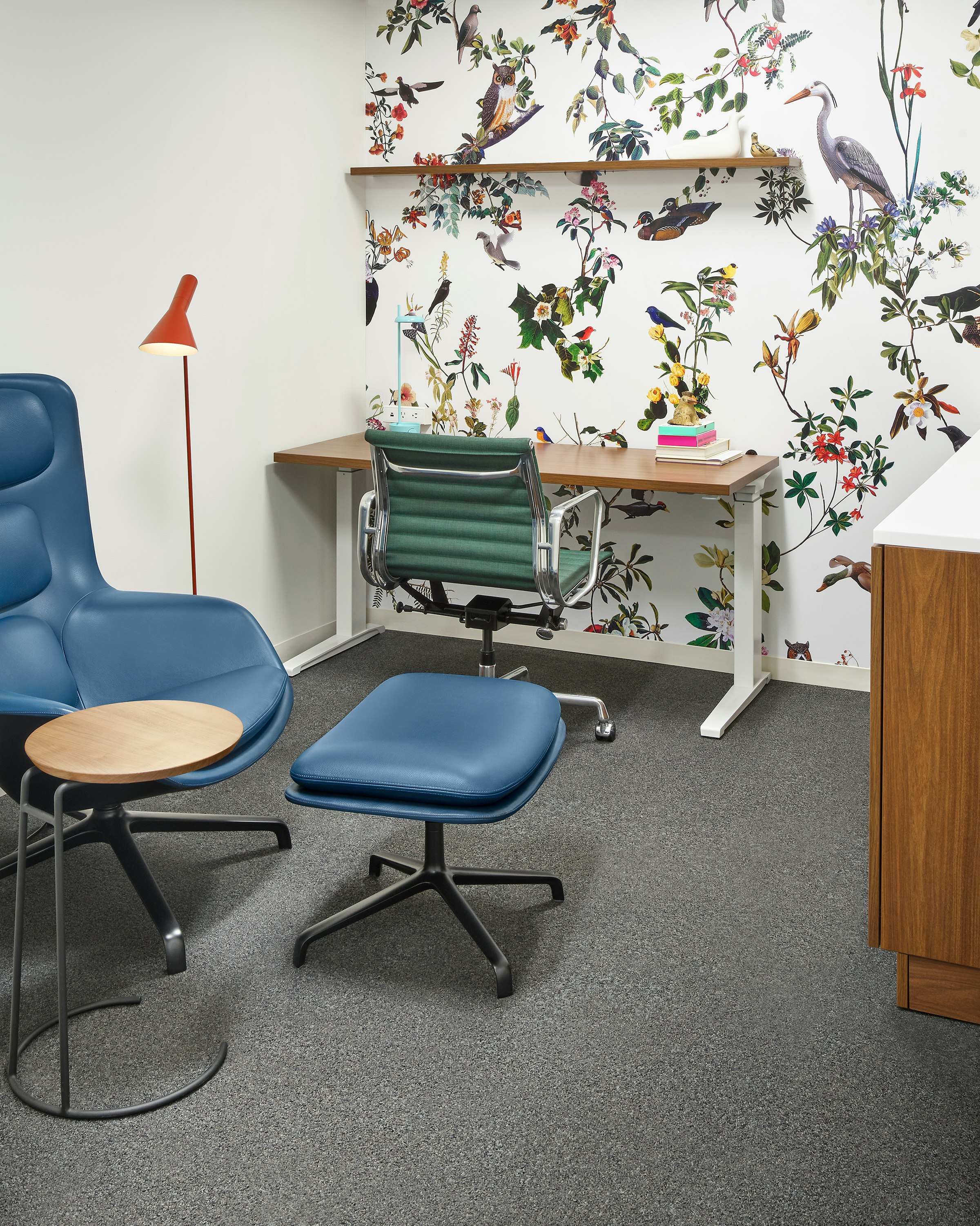 A mother's room set up with a Striad High back Lounge Chair and Ottoman next to a Renew Desk with an Eames Aluminum Group Management chair.