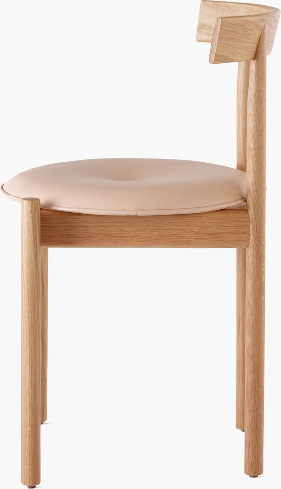Profile view of an oak Comma Chair with a seat pad.