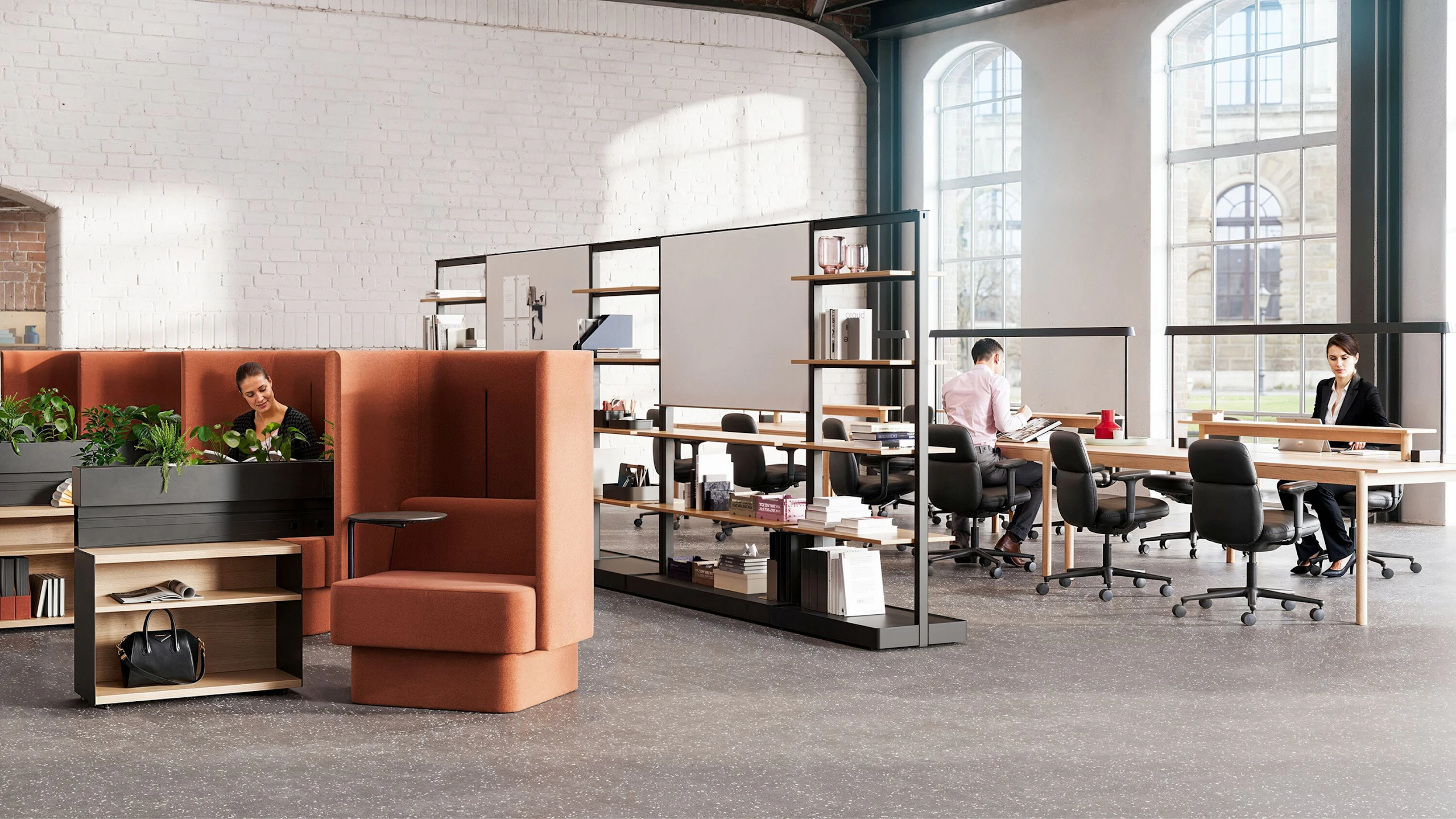 An individual reading in a burnt-orange NaughtOne Pullman chair next to Herman Miller OE1 Storage Trolleys in an individual study hall setting designed to cultivate an area of focus and wellbeing