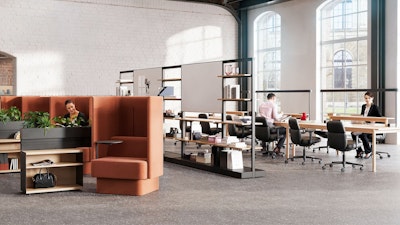 An individual reading in a burnt-orange NaughtOne Pullman chair next to Herman Miller OE1 Storage Trolleys in an individual study hall setting designed to cultivate an area of focus and wellbeing