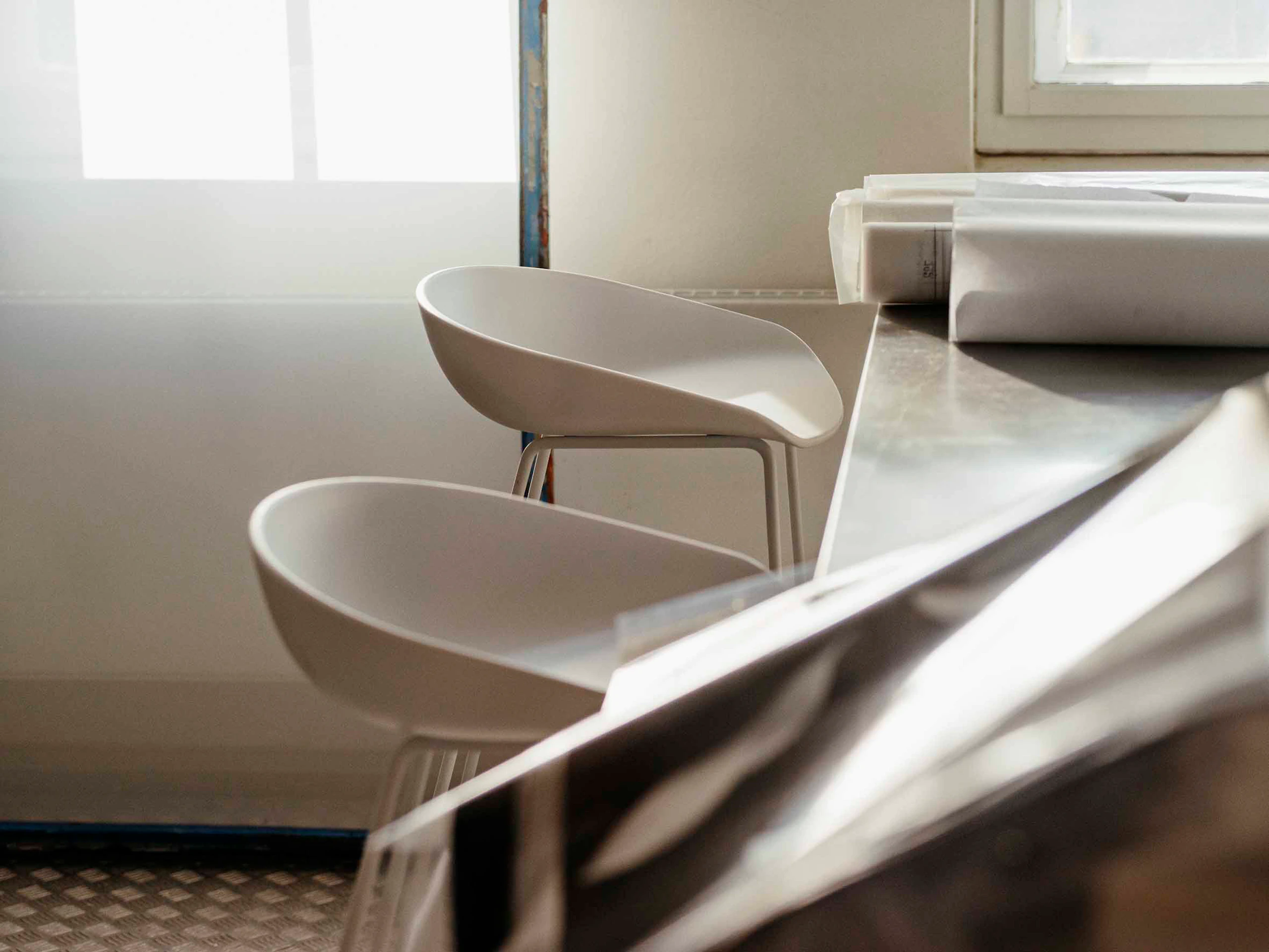 Two white About A Stools pulled up to a countertop.