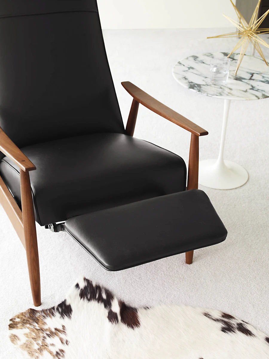 Close-up of a black leather reclining lounge chair with wooden arms and a matching footrest.