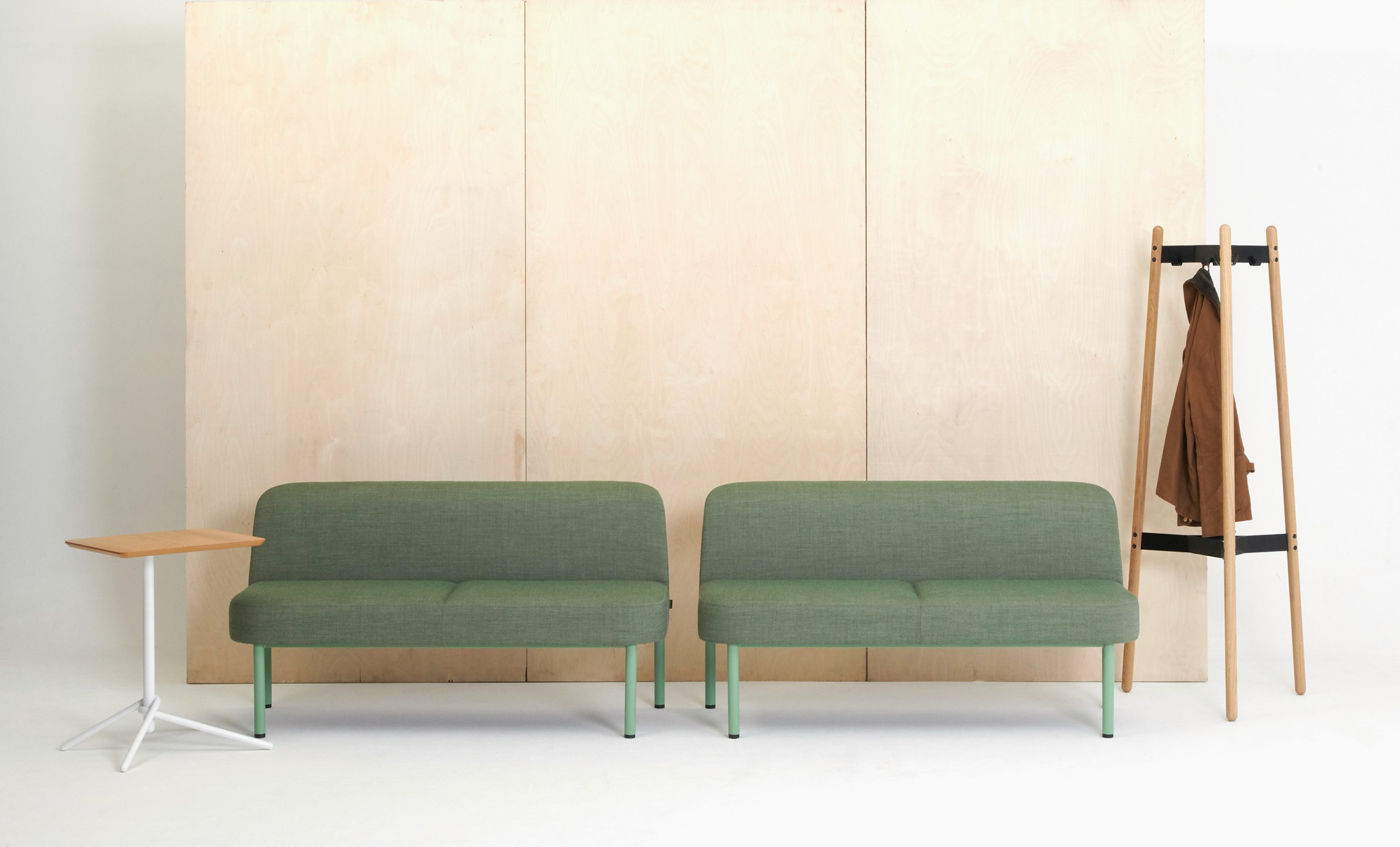 Two green Hue Sofas accompanied by a Knot Side Table and a Hudson Coatstand.