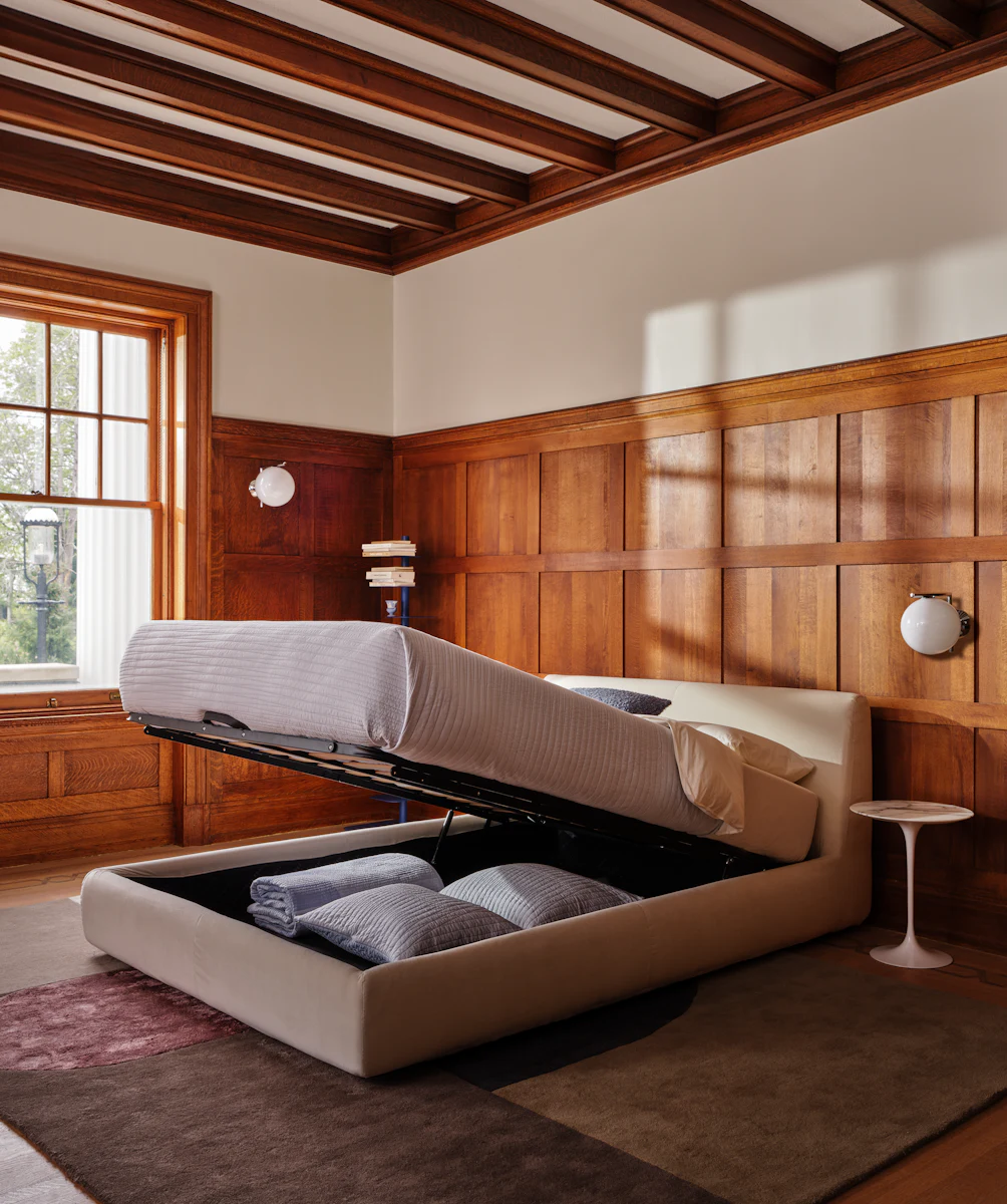 Cozy bedroom with wooden paneled walls, a low platform bed with white bedding and a window