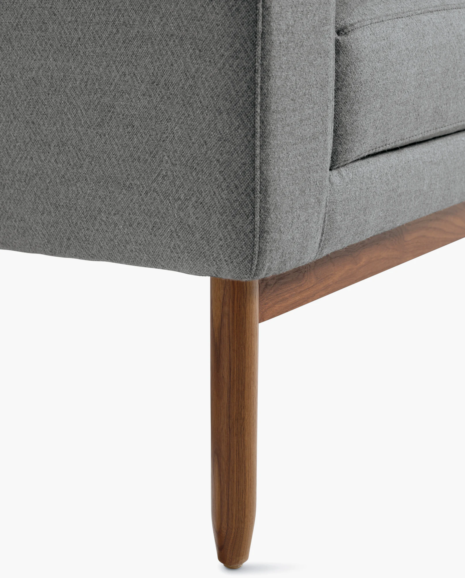Close-up of wood leg and upholstered base of dark navy armchair