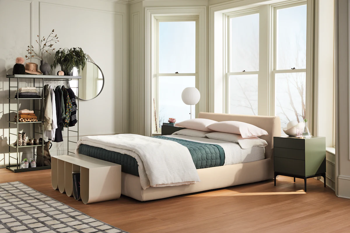 Bedroom with dark accent wall, bed with storage drawers and flowers on nightstand