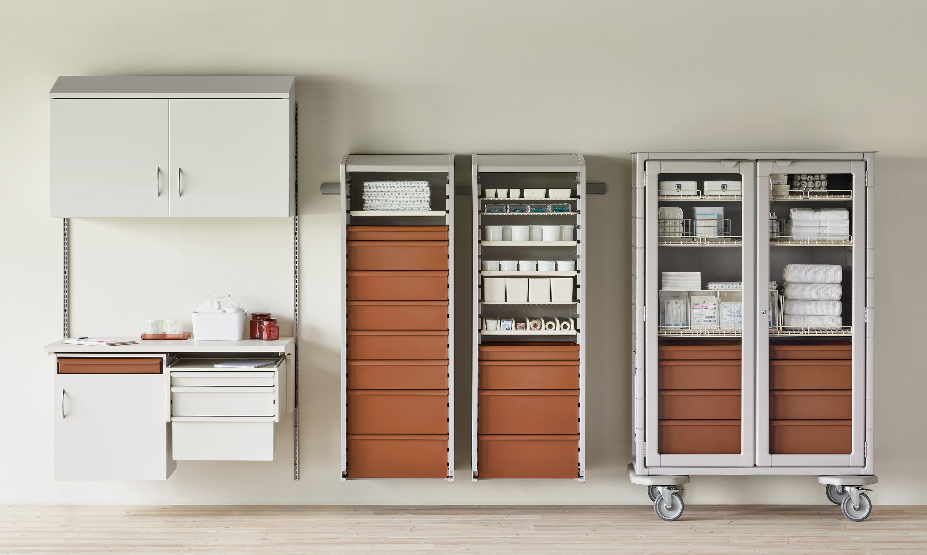 Medical clean supply room featuring a double-wide Procedure and Supply Cart with glass doors, next to a soft white Co/Struc System and lockers with terra cotta drawers.