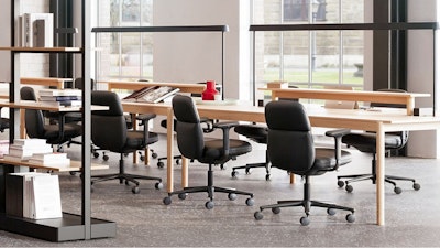 Several black Herman Miller Asari Chairs placed around a Muuto Linear System and Mounted Lamps allowing team members to connect while working individually.