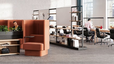 An individual reading in a burnt-orange NaughtOne Pullman chair next to Herman Miller OE1 Storage Trolleys in an individual study hall setting designed to cultivate an area of focus and wellbeing