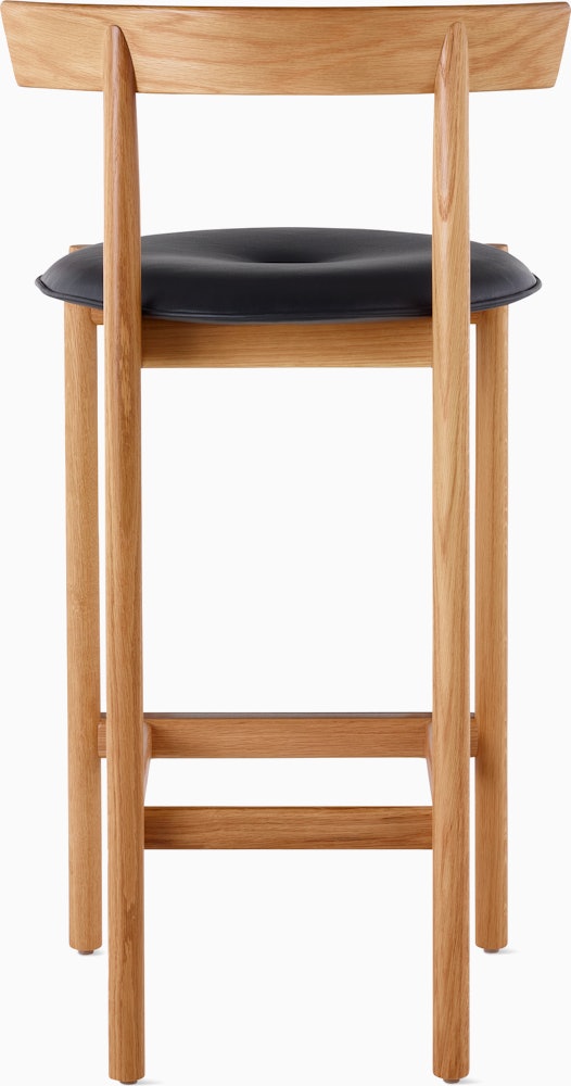 An oak Comma Stool with a seat pad, viewed from the back.
