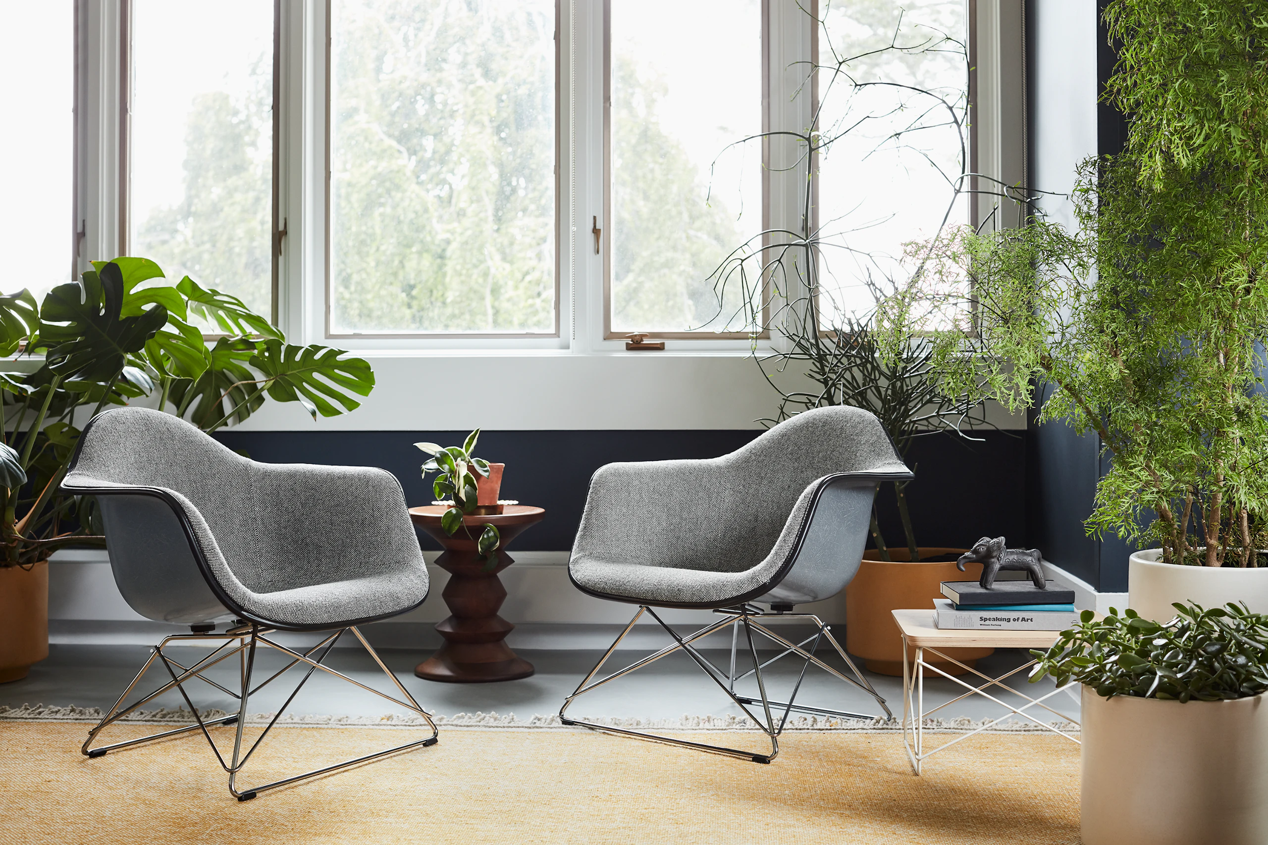 Two Eames Molded Fiberglass Upholstered Armchairs with low wire bases in a casual lounge setting.