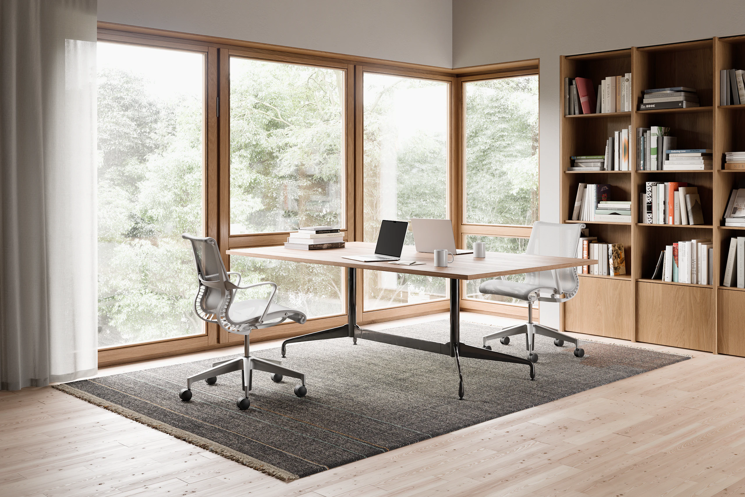 Two Setu chairs in light grey on opposite sides of a rectangular table in a home office with a bookshelf.