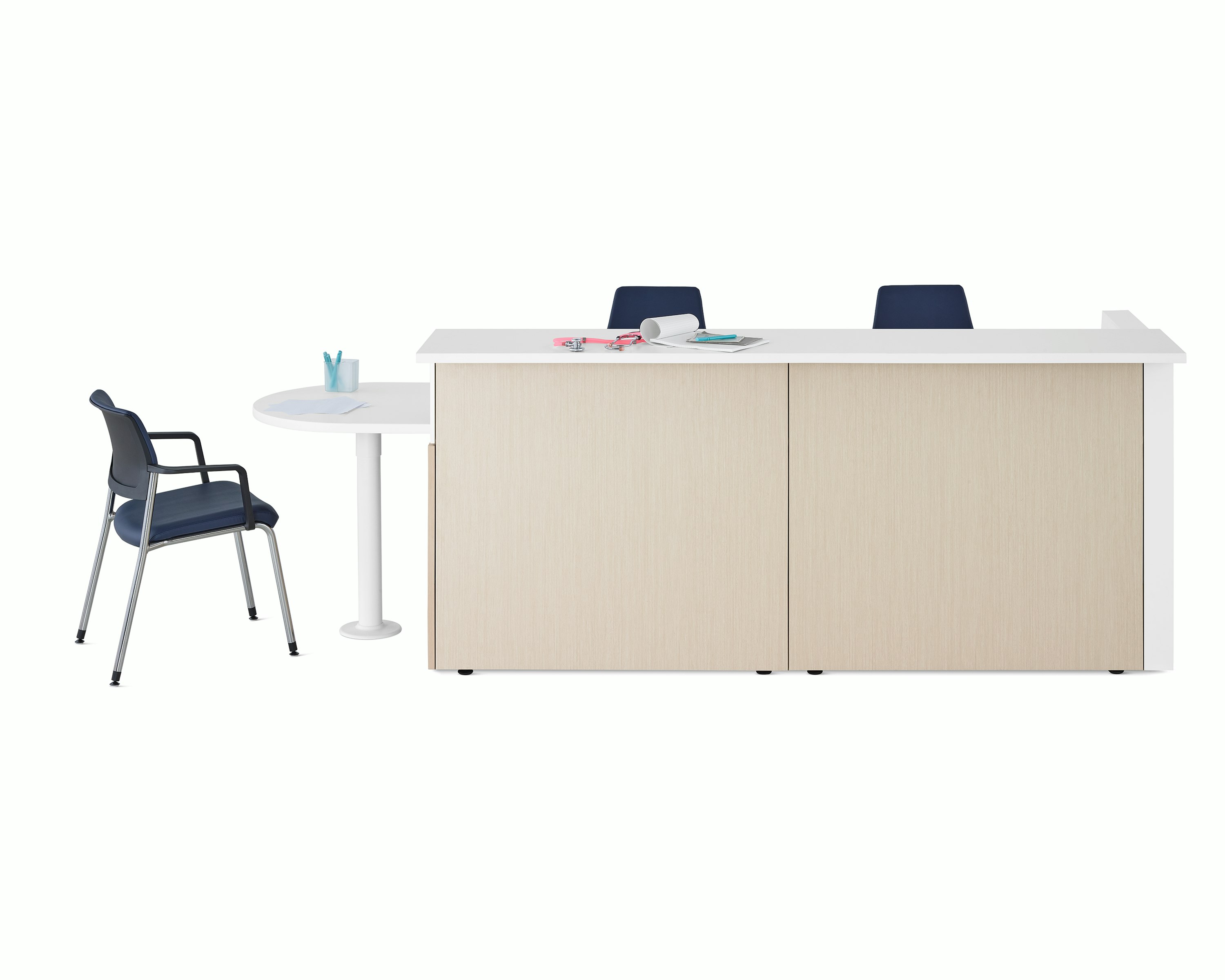 Ethospace Nurses Station in a light wood finish with transaction surface and ADA peninsula surface in white, a Verus Side Chair in blue, and Sayl Chairs in blue.