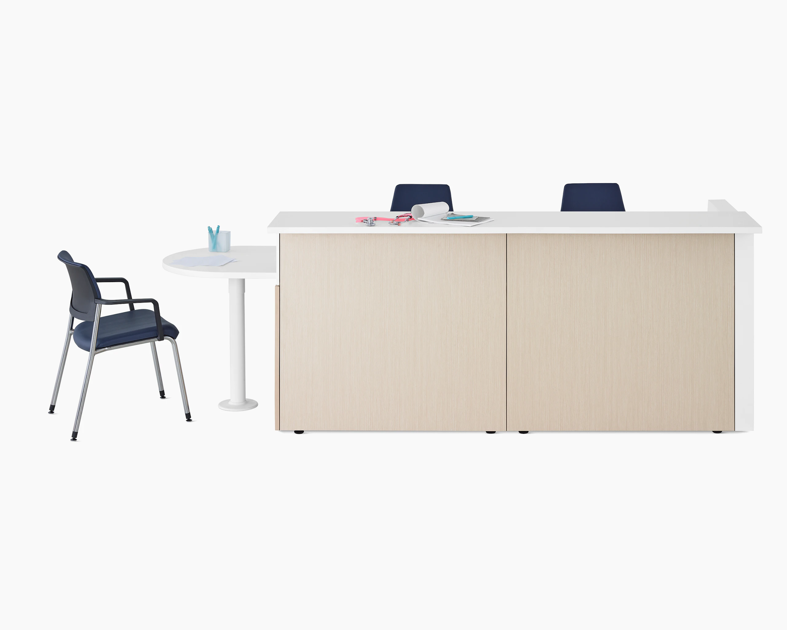 Ethospace Nurses Station in a light wood finish with transaction surface and ADA peninsula surface in white, a Verus Side Chair in blue, and Sayl Chairs in blue.