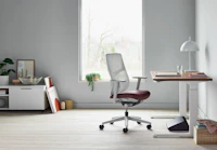 A side view of black Foot Pillow, under a Renew Sit-to-Stand Table with a Verus Chair.