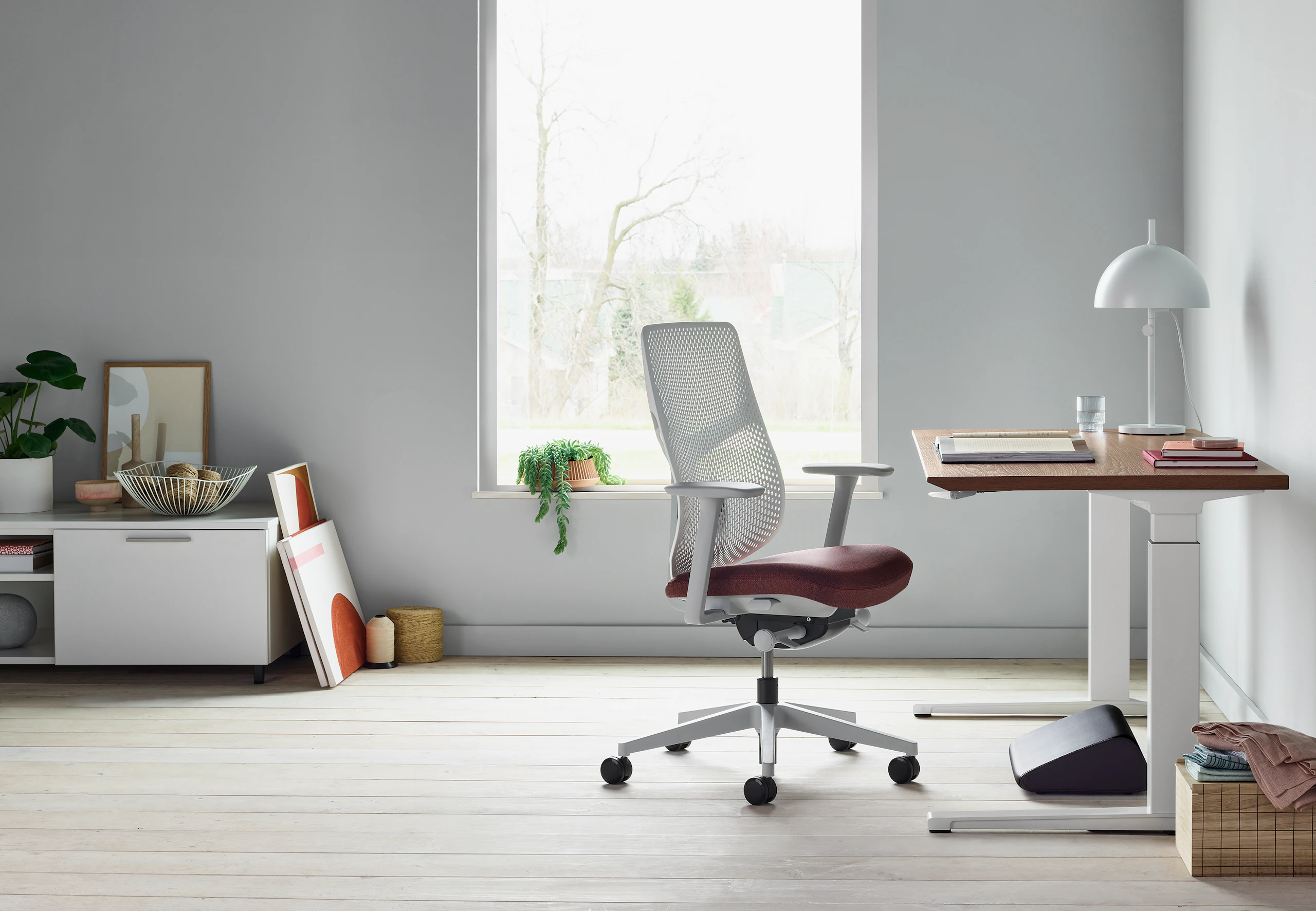 A side view of black Foot Pillow, under a Renew Sit-to-Stand Table with a Verus Chair.