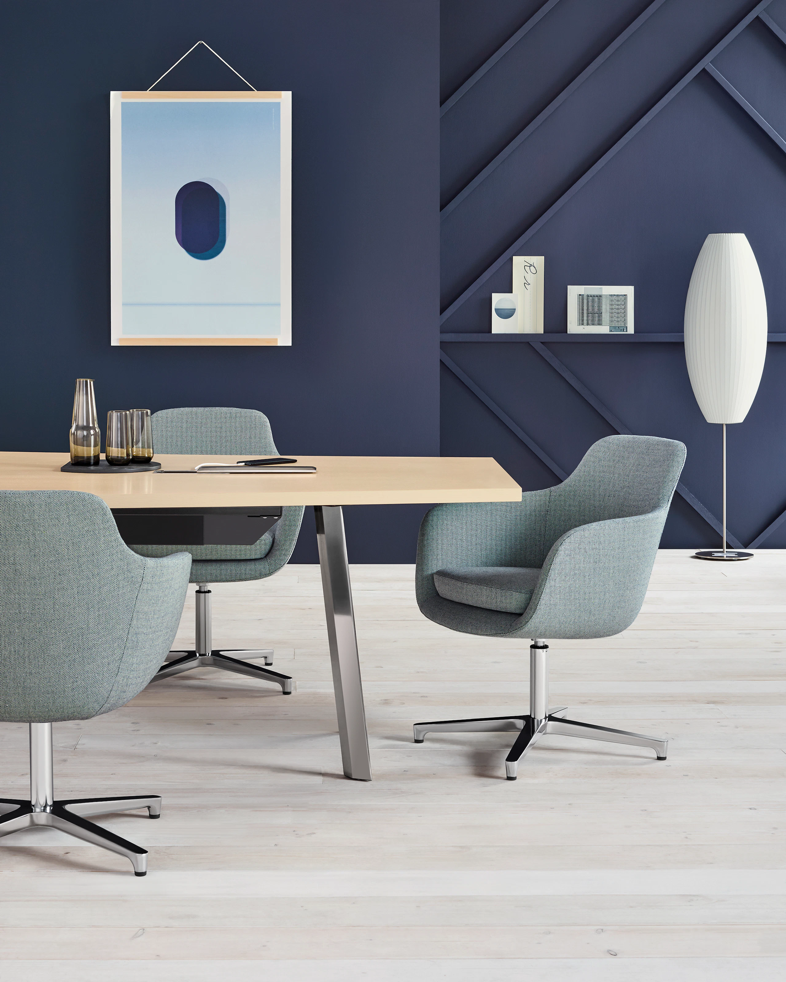 Partial view of a rectangular Geiger Elsi conference table with three gray Saiba office chairs.