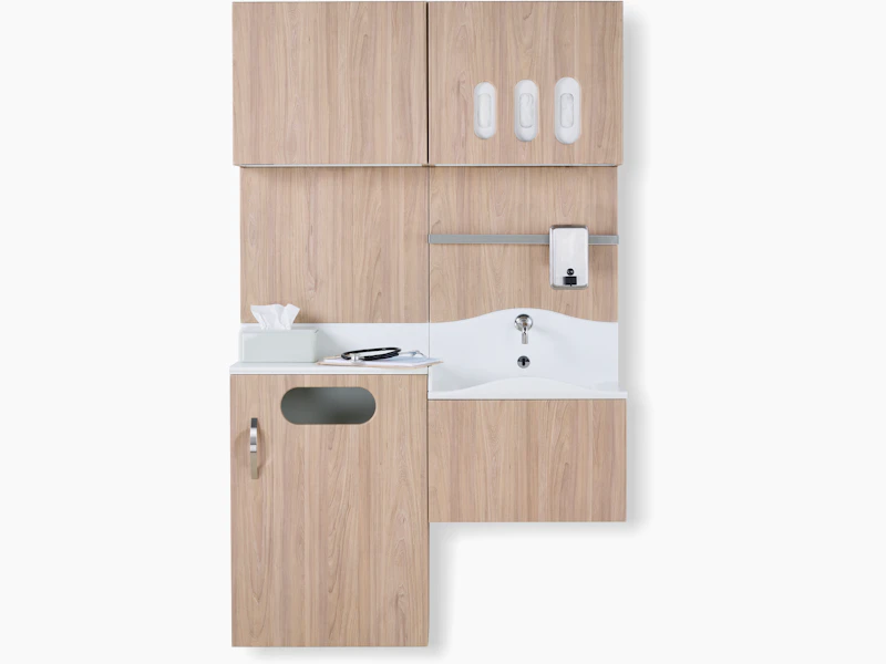 Front view of Compass System casework wall unit in a medium elm wood laminate finish with integrated waste receptacle, white solid surface sink, and upper storage for gloves.