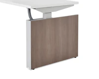 Exterior view of dark wood shroud attached to a height adjustable table with a mesh vertical wire manager.