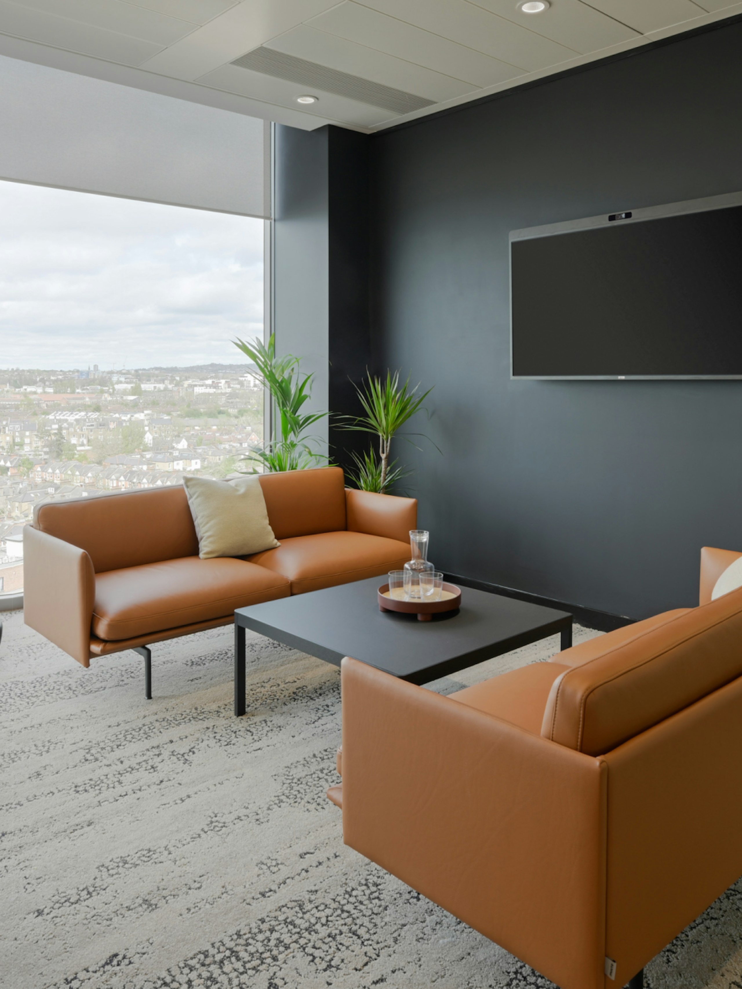 Two leather Outline Sofas by Muuto arranged around a black coffee table in a meeting space overlooking London at the NATO Defence Innovation Accelerator