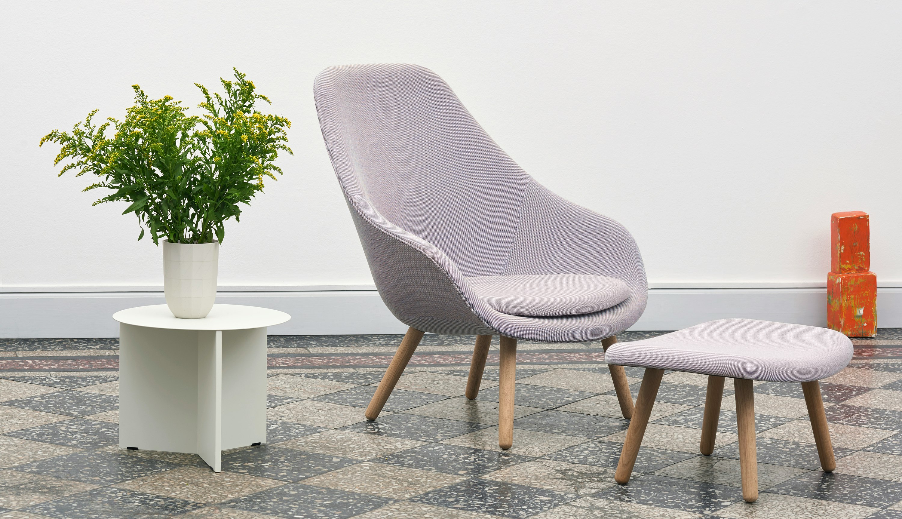 White, round Slit Table alongside purple About a Lounge Chair and Ottoman.