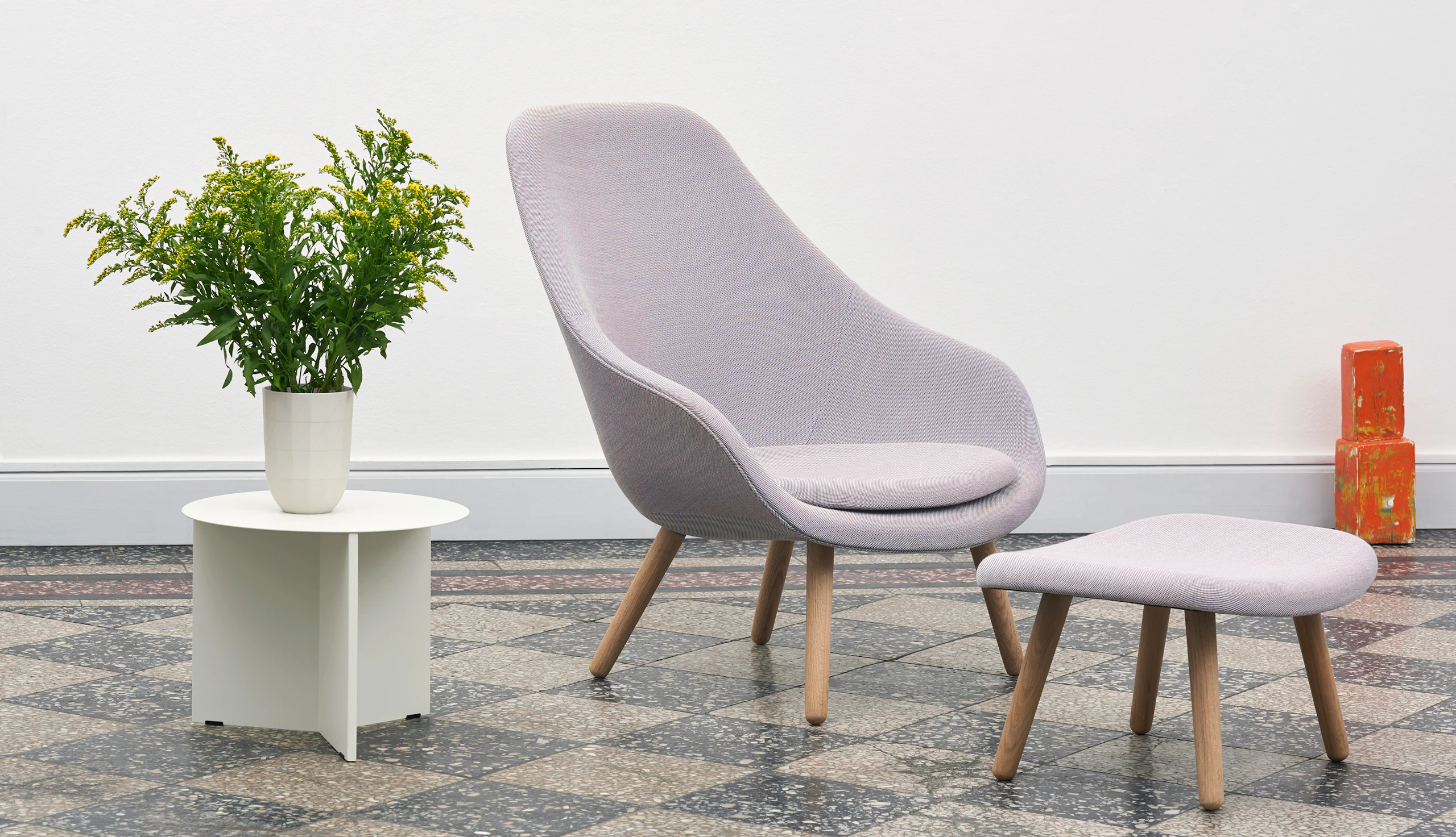 White, round Slit Table alongside purple About a Lounge Chair and Ottoman.