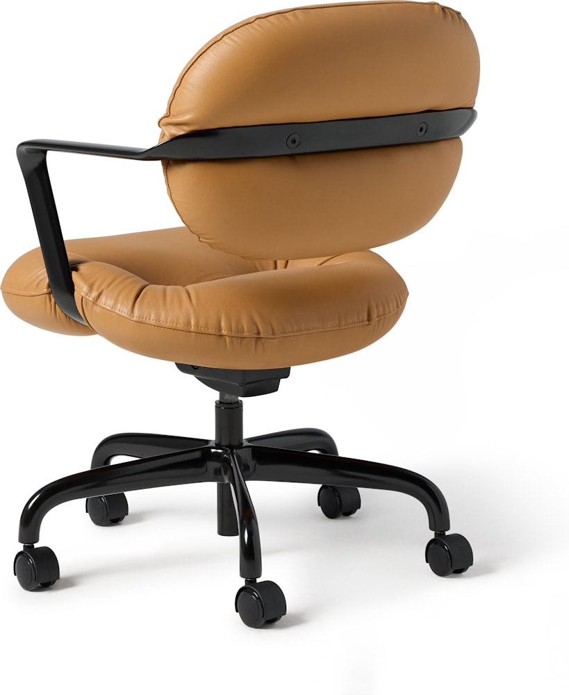 Rear angle view of a Morrison Hannah chair with a black frame and base with fixed arms and light brown leather upholstery.