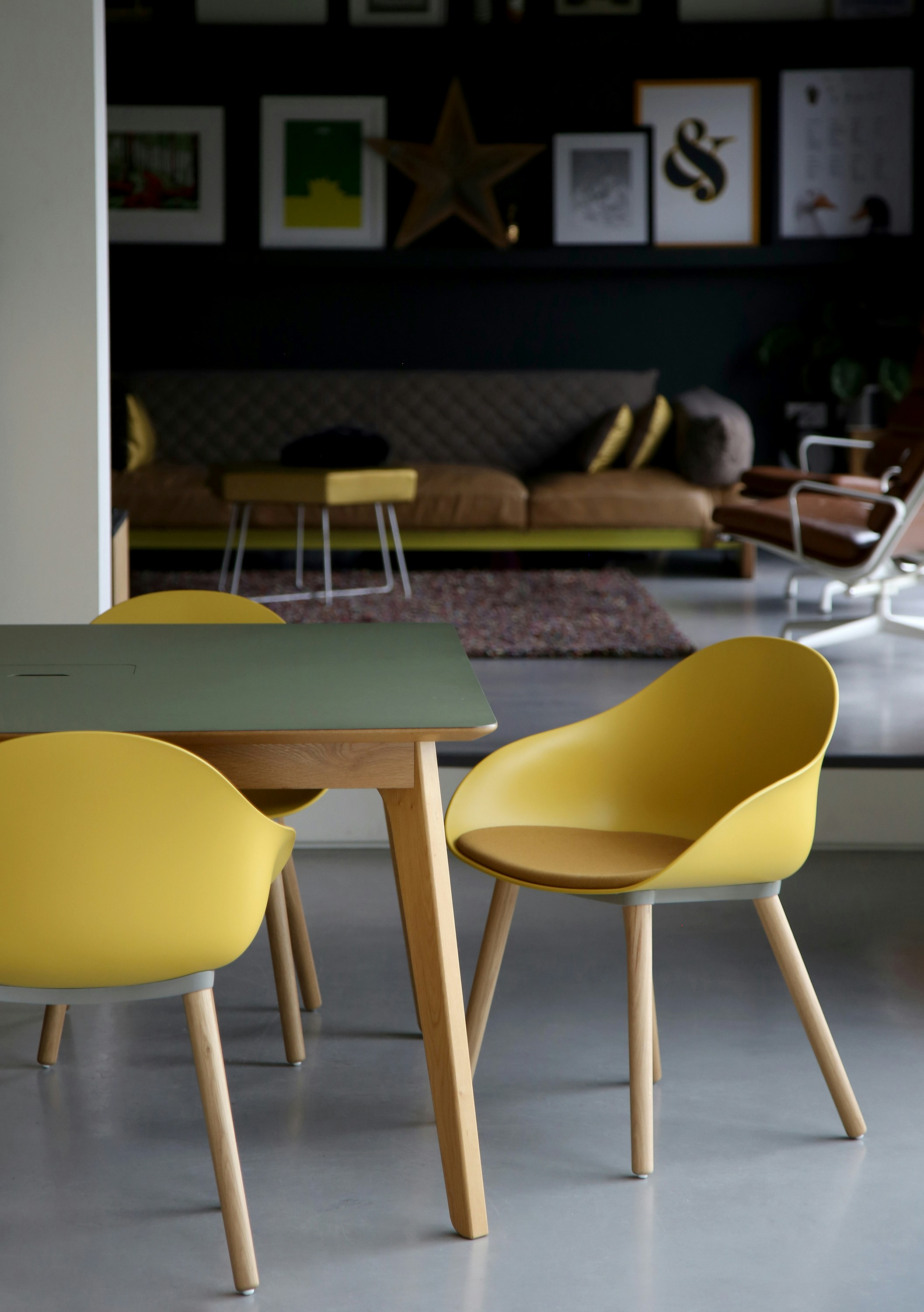 Three yellow Ruby Side Chairs on oak dowel bases with a table.