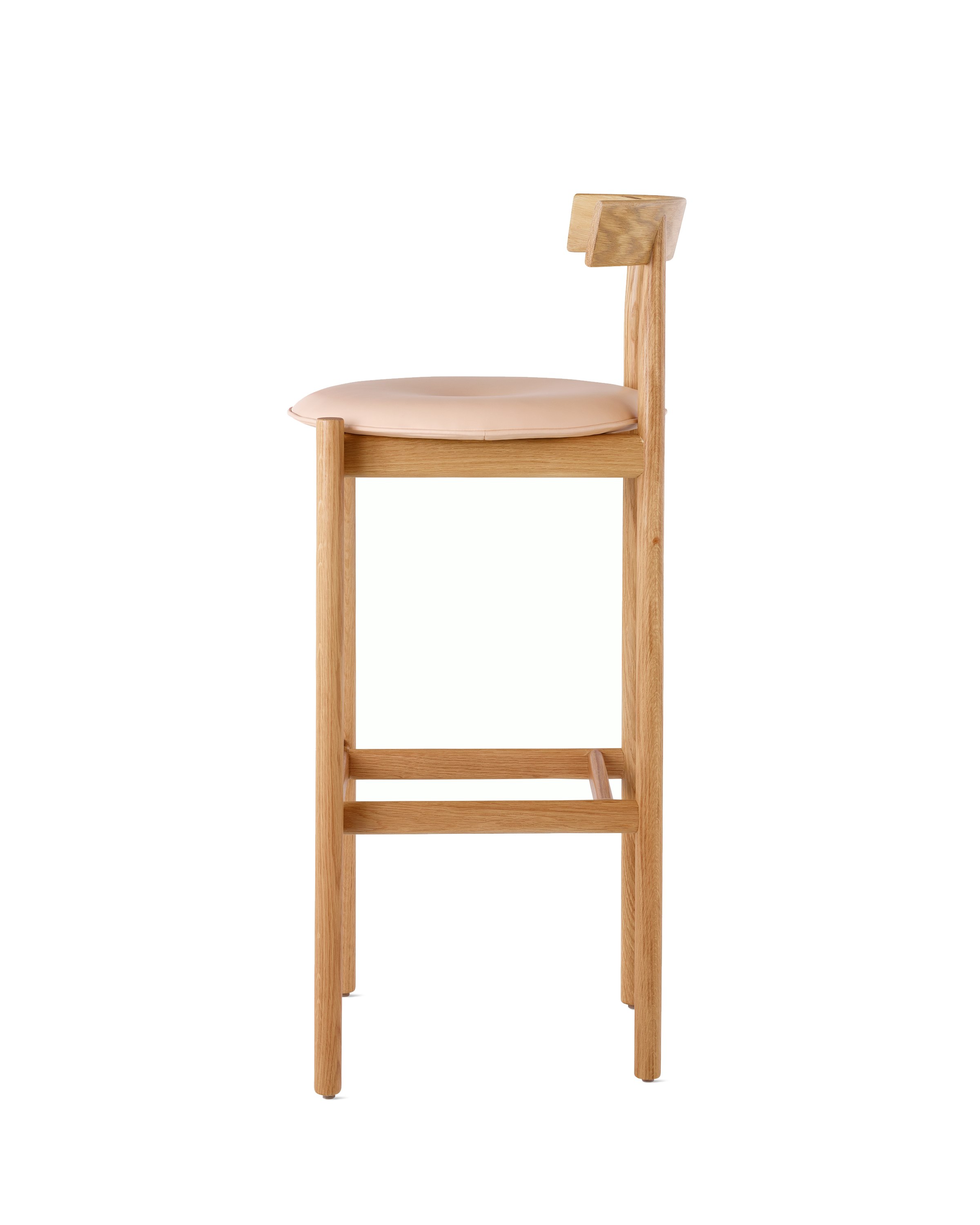 Profile view of an oak bar-height Comma Stool with a seat pad.