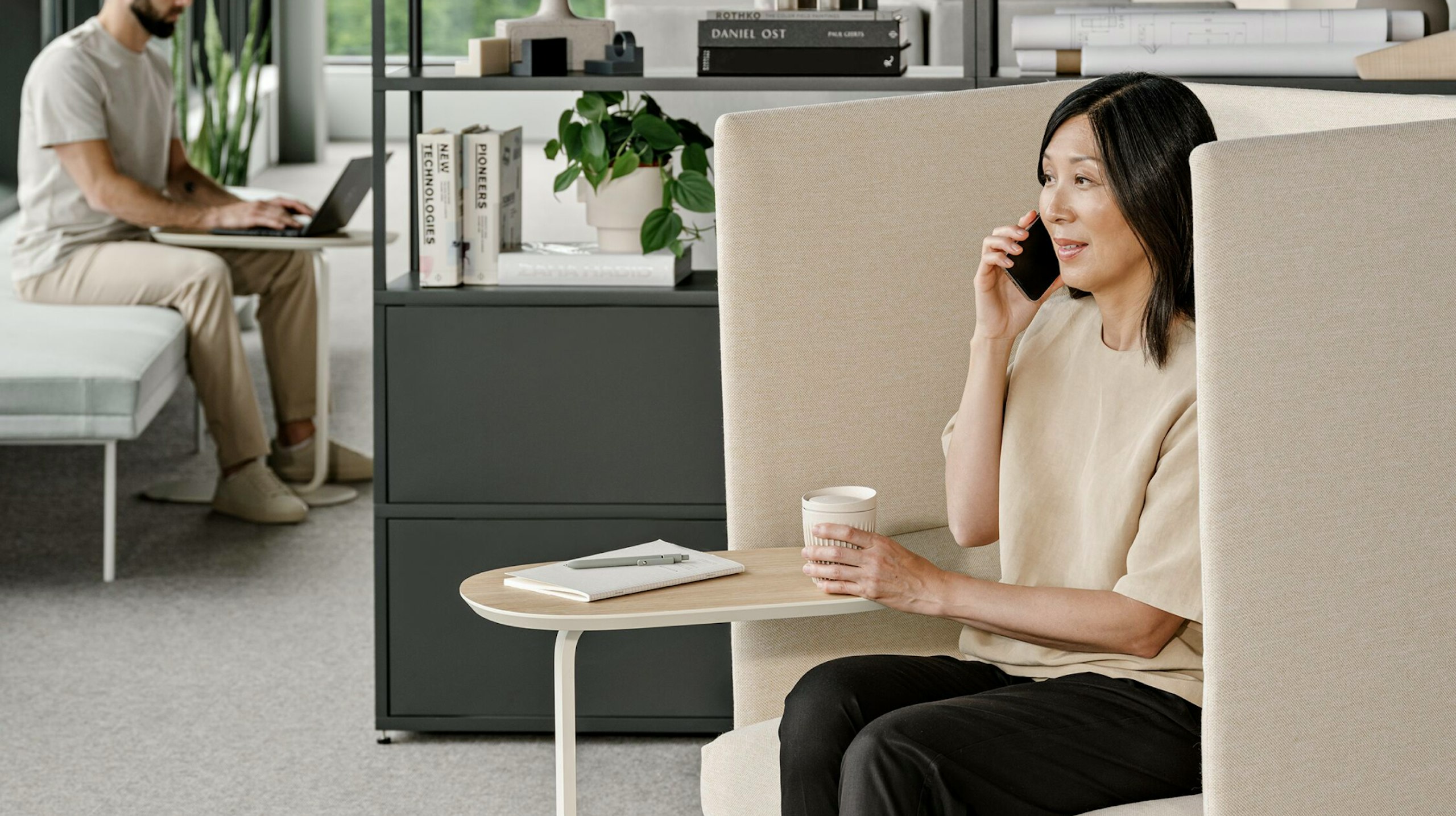 A person talking on the phone while seated in a beige NaughtOne Pullman chair