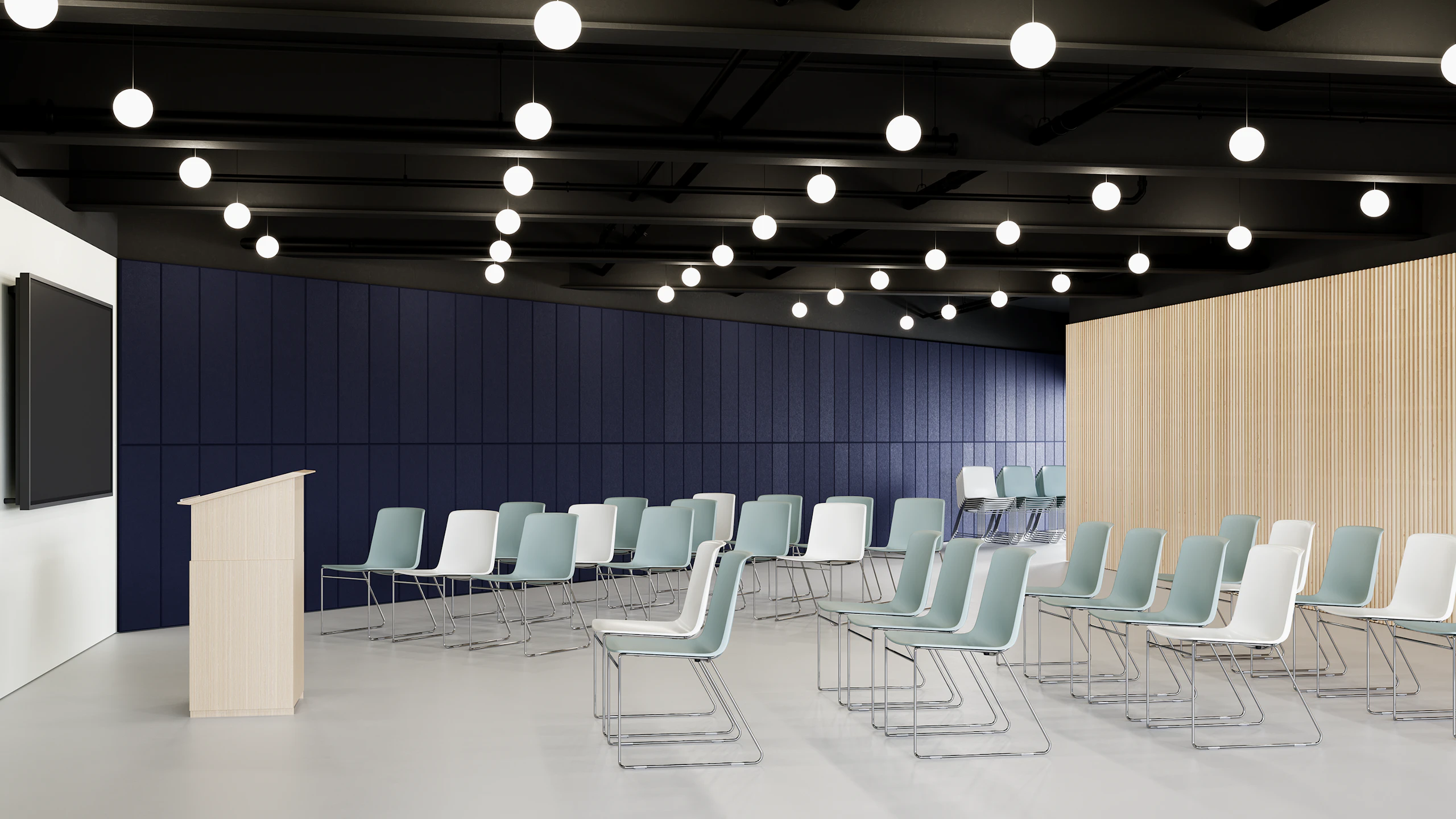 An auditorium filled with white and glacier colored Pronta Stacking Chairs, with a tv monitor and podium in front.