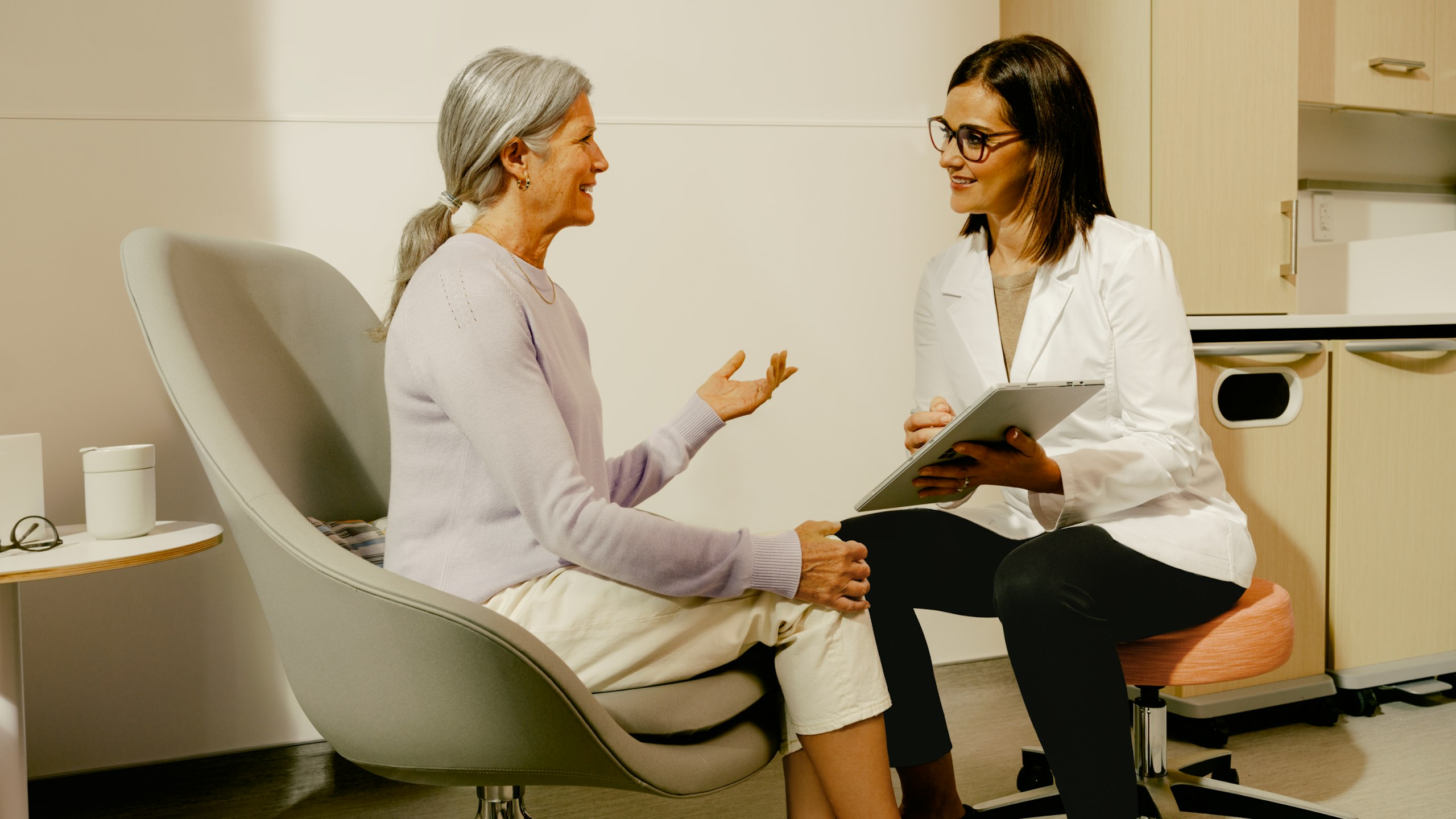 Female patient in an exam room with a female physician having a conversation.
