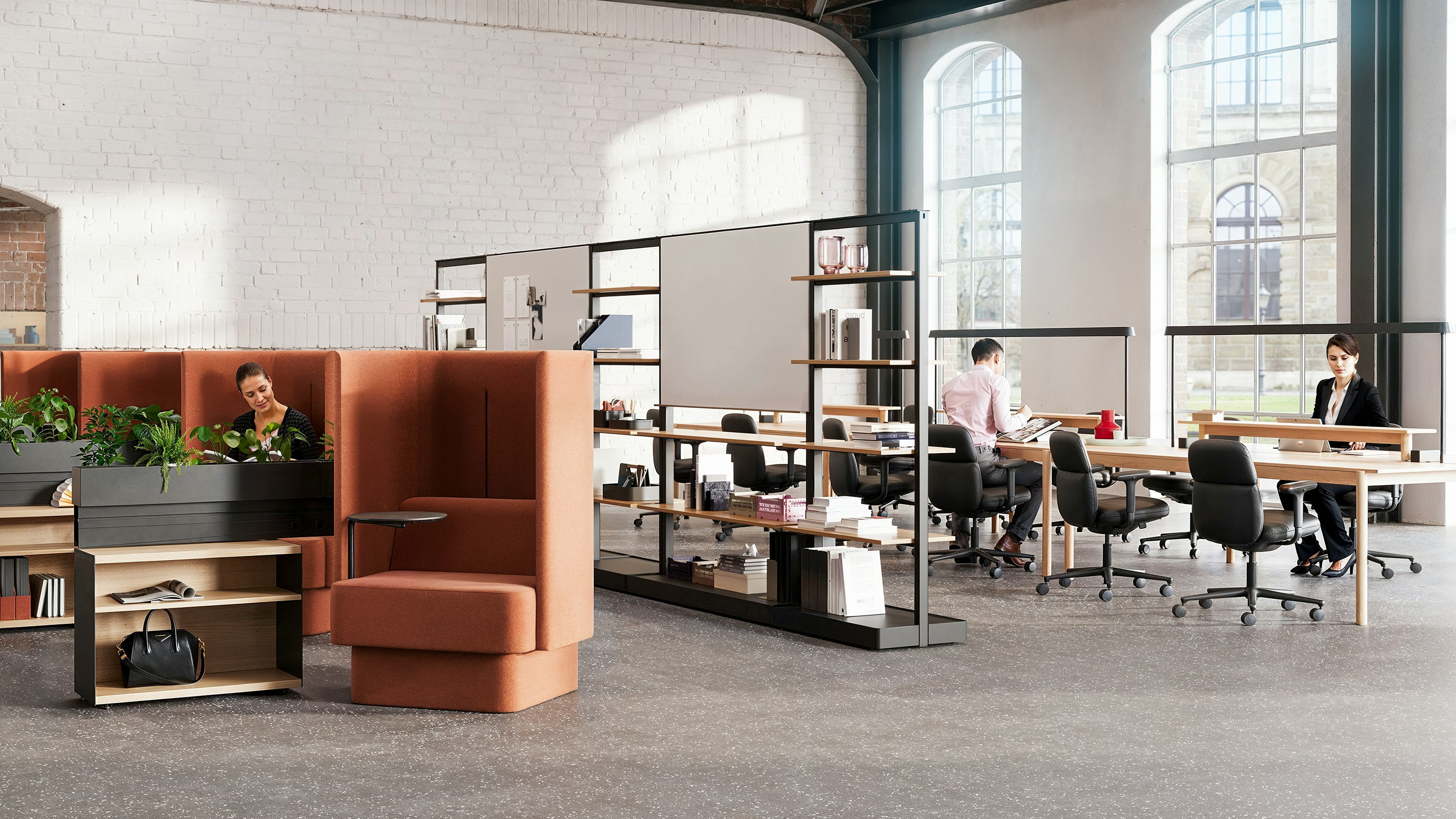 Study hall setting with large windows, white brick walls, NaughtOne Pullman Chairs, a Muuto Linear System Series and Mounted Lamps, and Herman Miller Asari Chairs.