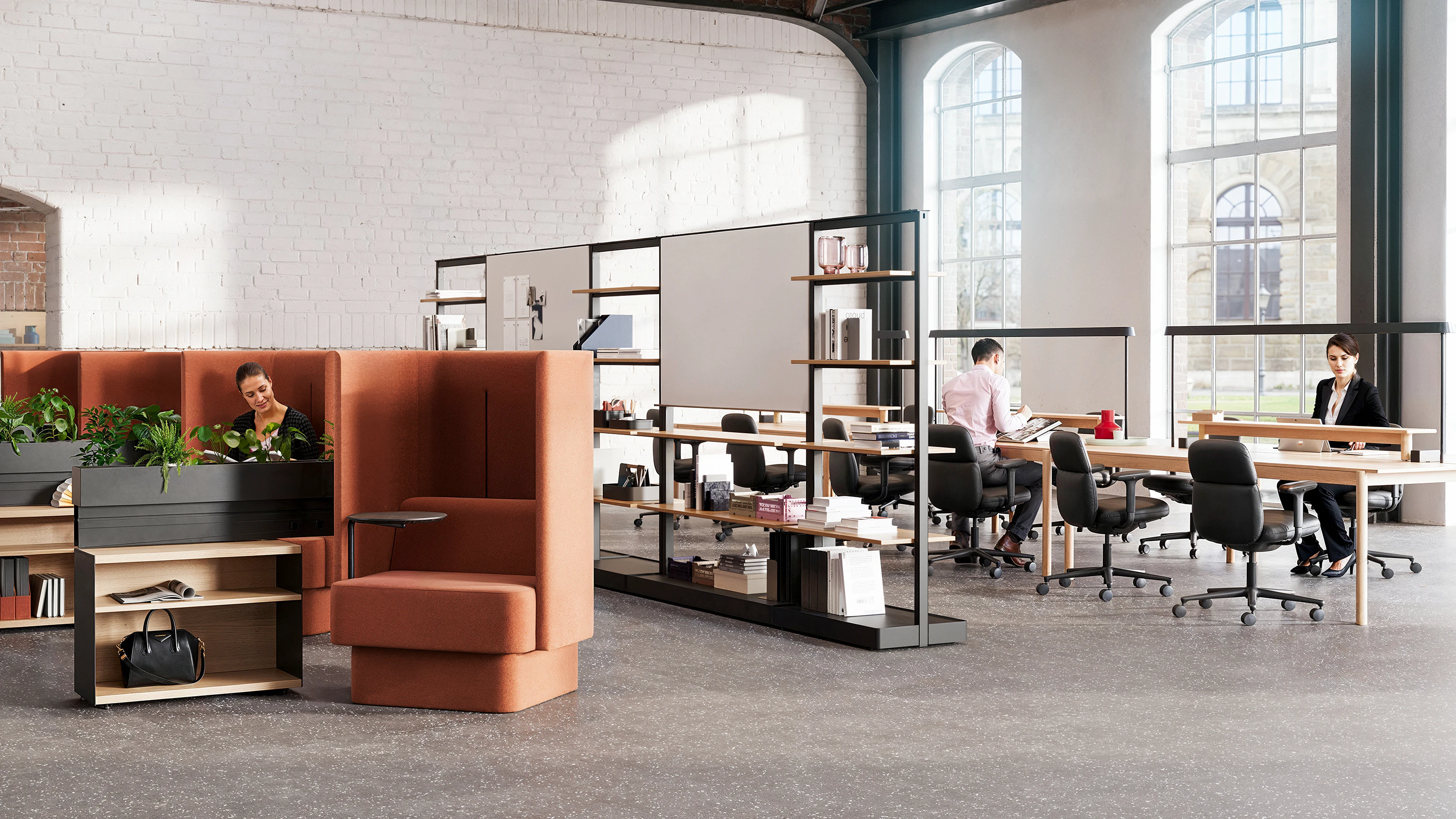 Study hall setting with large windows, white brick walls, NaughtOne Pullman Chairs, a Muuto Linear System Series and Mounted Lamps, and Herman Miller Asari Chairs.