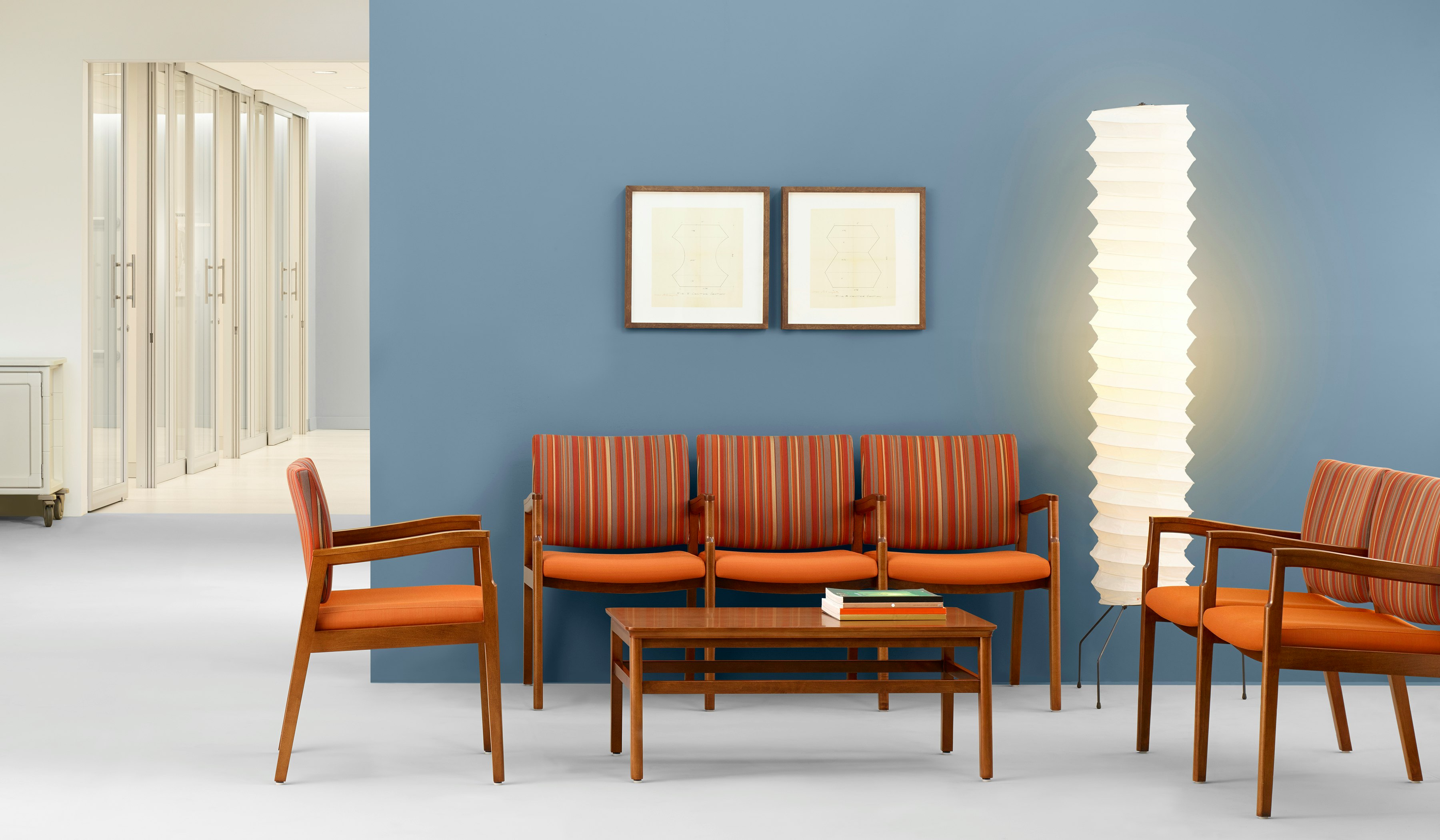 A waiting room with blue wall featuring Monarch Multiple seating in orange and striped textile.