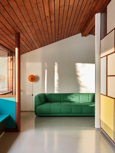 A living space with a green Quilton Sofa and Matin Flushmount Light by Hay.