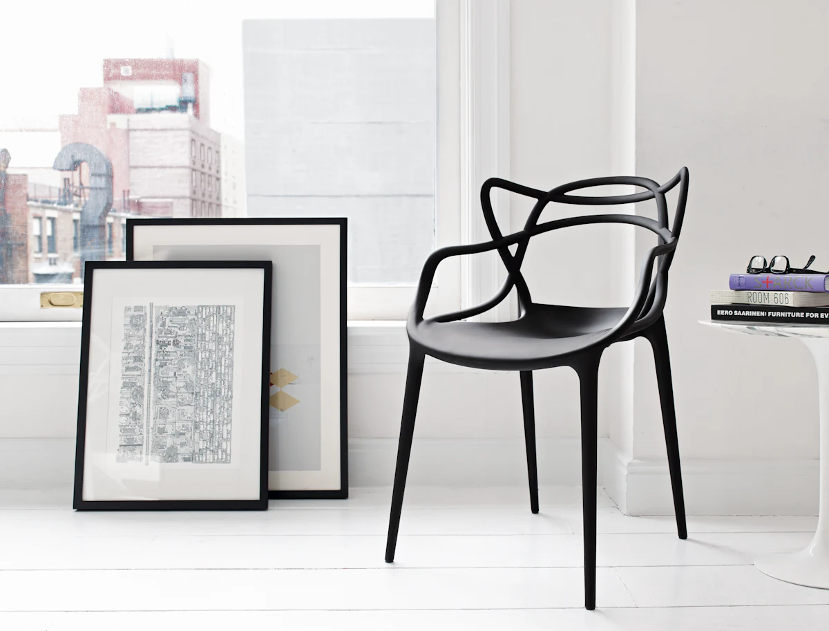 A white chair with an intricate interwoven backrest in a minimal room setting.