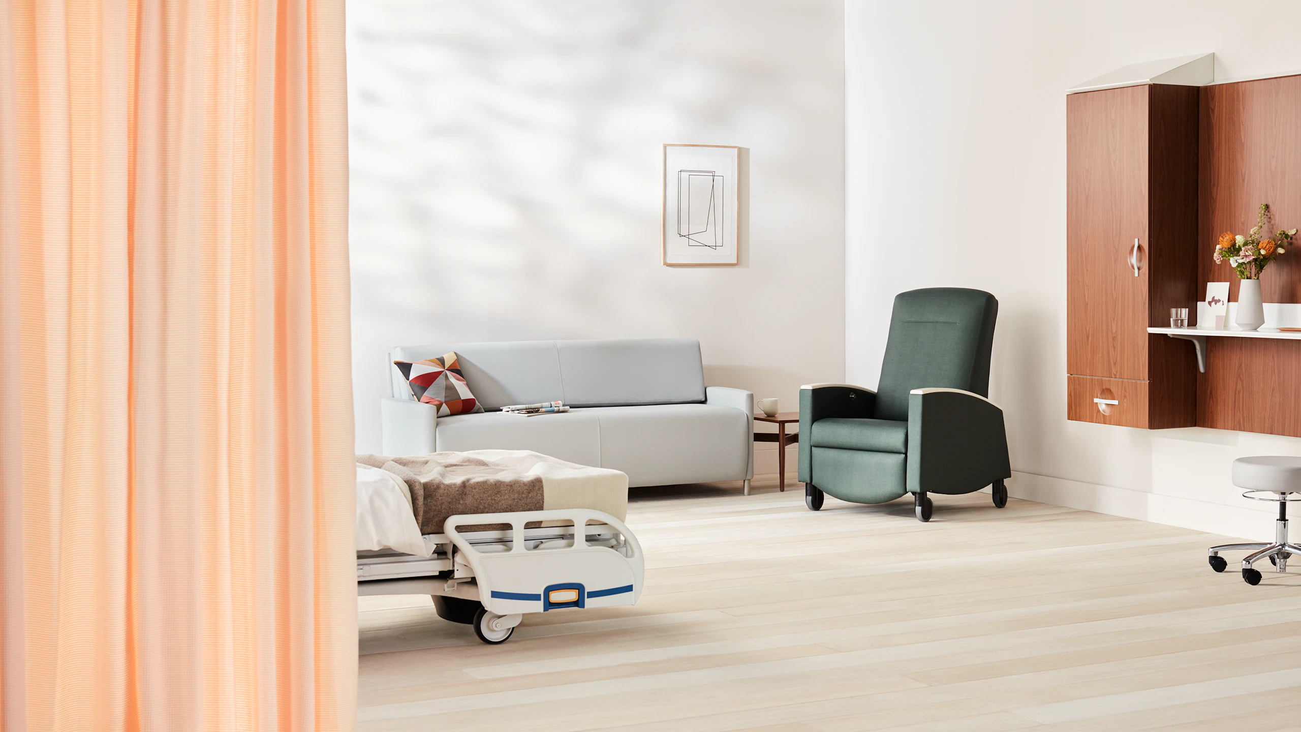 Patient Room with Compass footwall in a medium walnut with a light gray Pamona Flop Sofa and a dark green Sahara recliner.