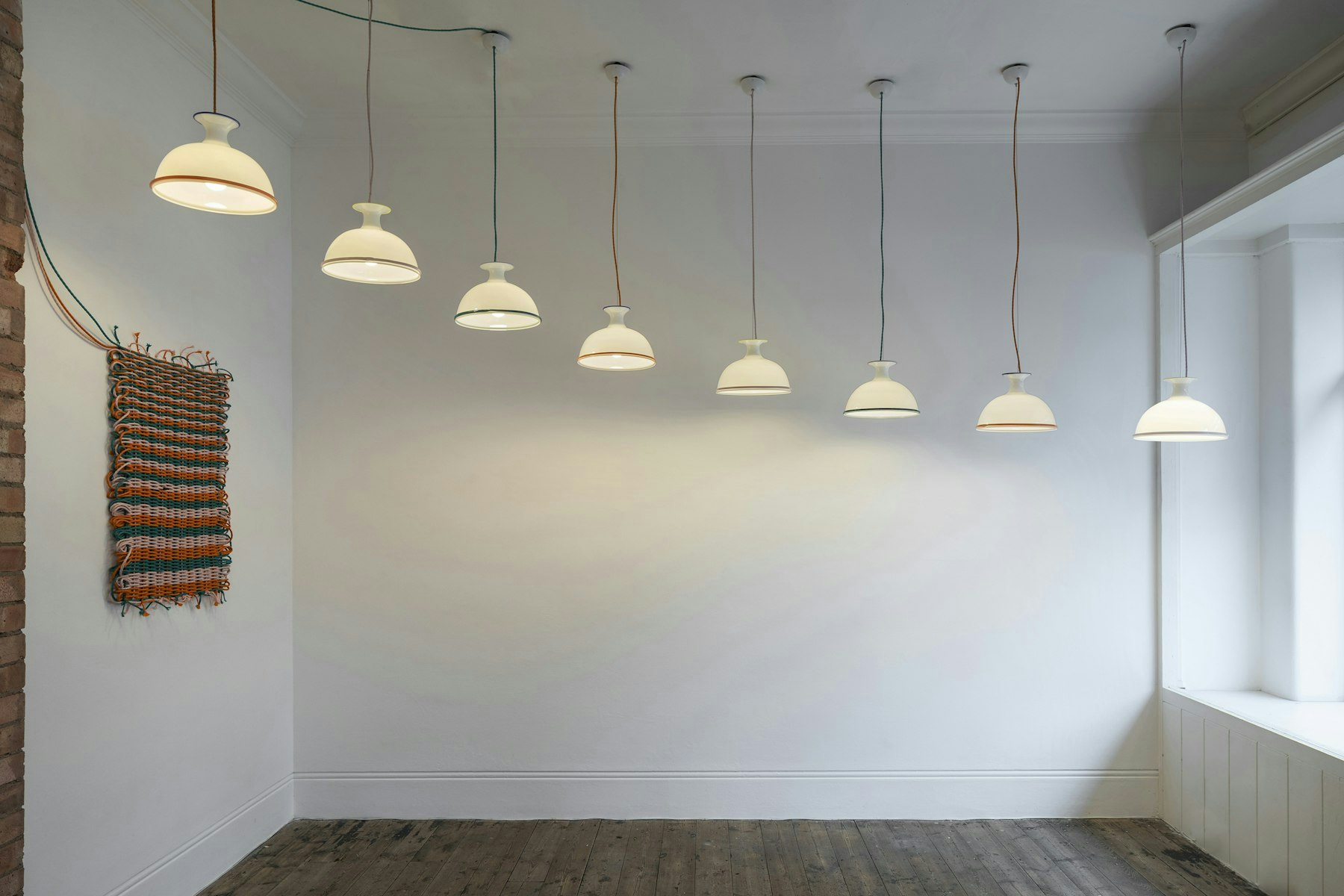 Eight assorted Mark Pendant Lights hanging from a living room ceiling