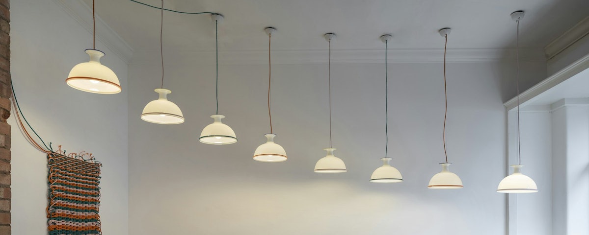 Eight assorted Mark Pendant Lights hanging from a living room ceiling
