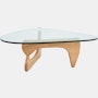 A Noguchi Table with light wood base and glass top.