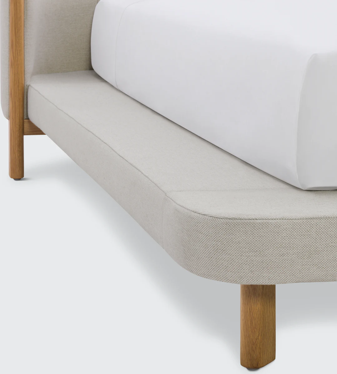 Side view of a platform bed with light fabric panels and wooden legs.