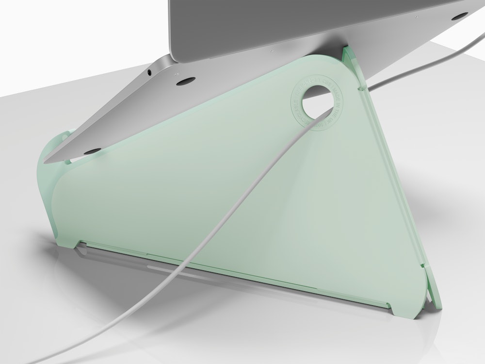 The back of an Oripura Laptop Stand in mint green with a power cable routed through its cable slots.