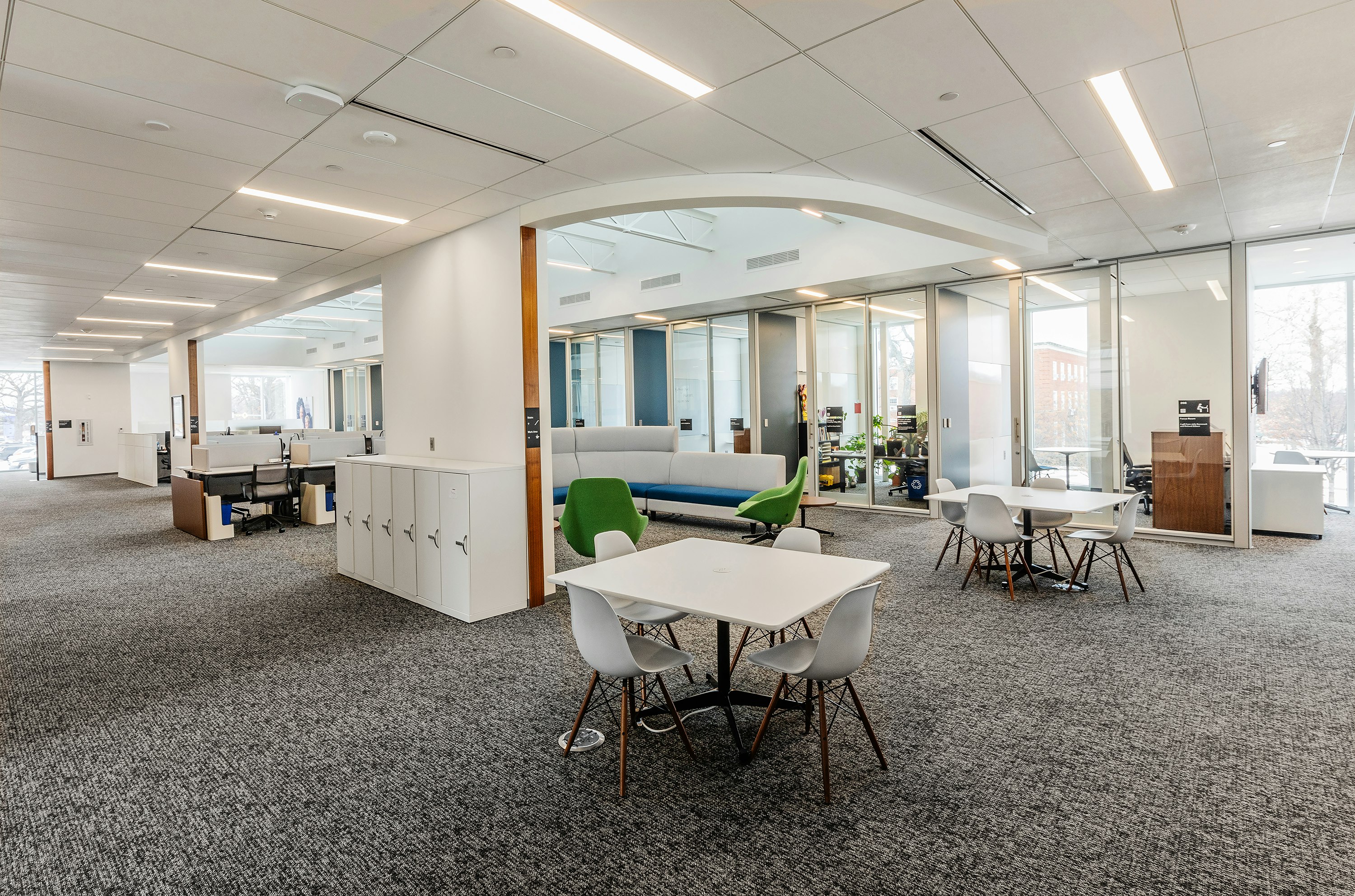 Small group collaboration areas in an academic research institute with square tables and four chairs around them.
