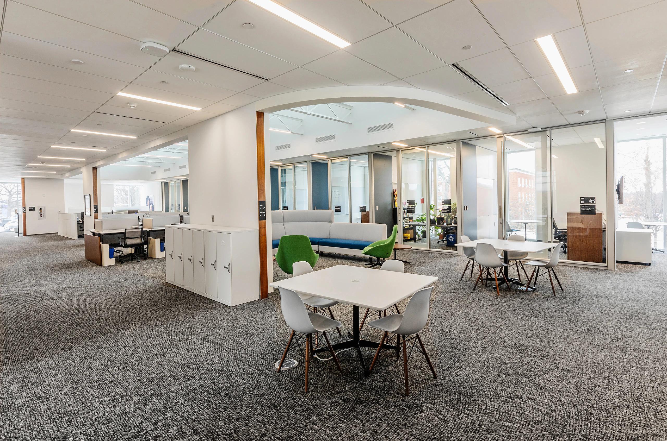 Small group collaboration areas in an academic research institute with square tables and four chairs around them.