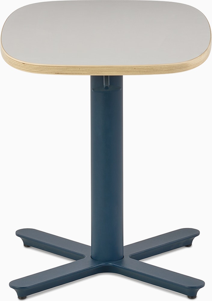 Small Passport Work Table with white surface, plywood edge and dark blue base shown on glides.