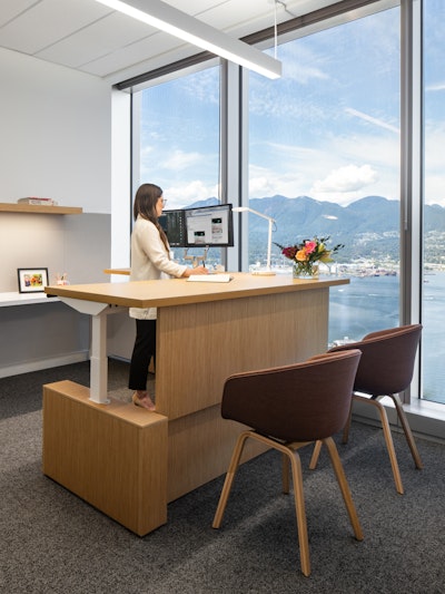 A person working at a sit-to-stand table in a private office furnished with HAY About A chairs